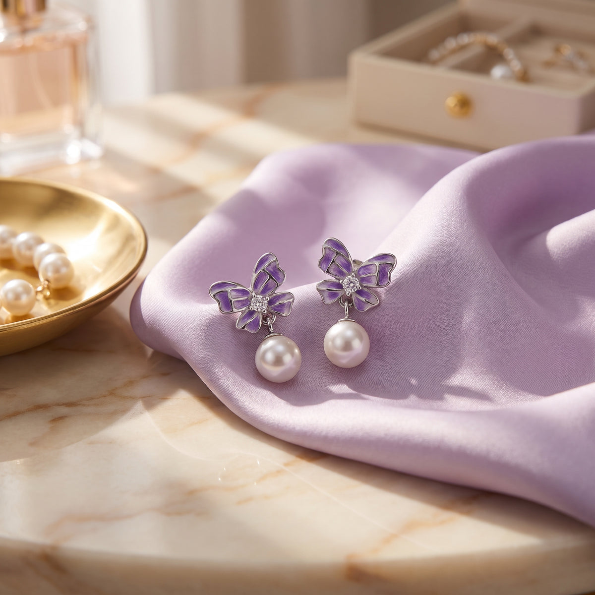Purple butterfly pearl drop earrings styled on lilac satin