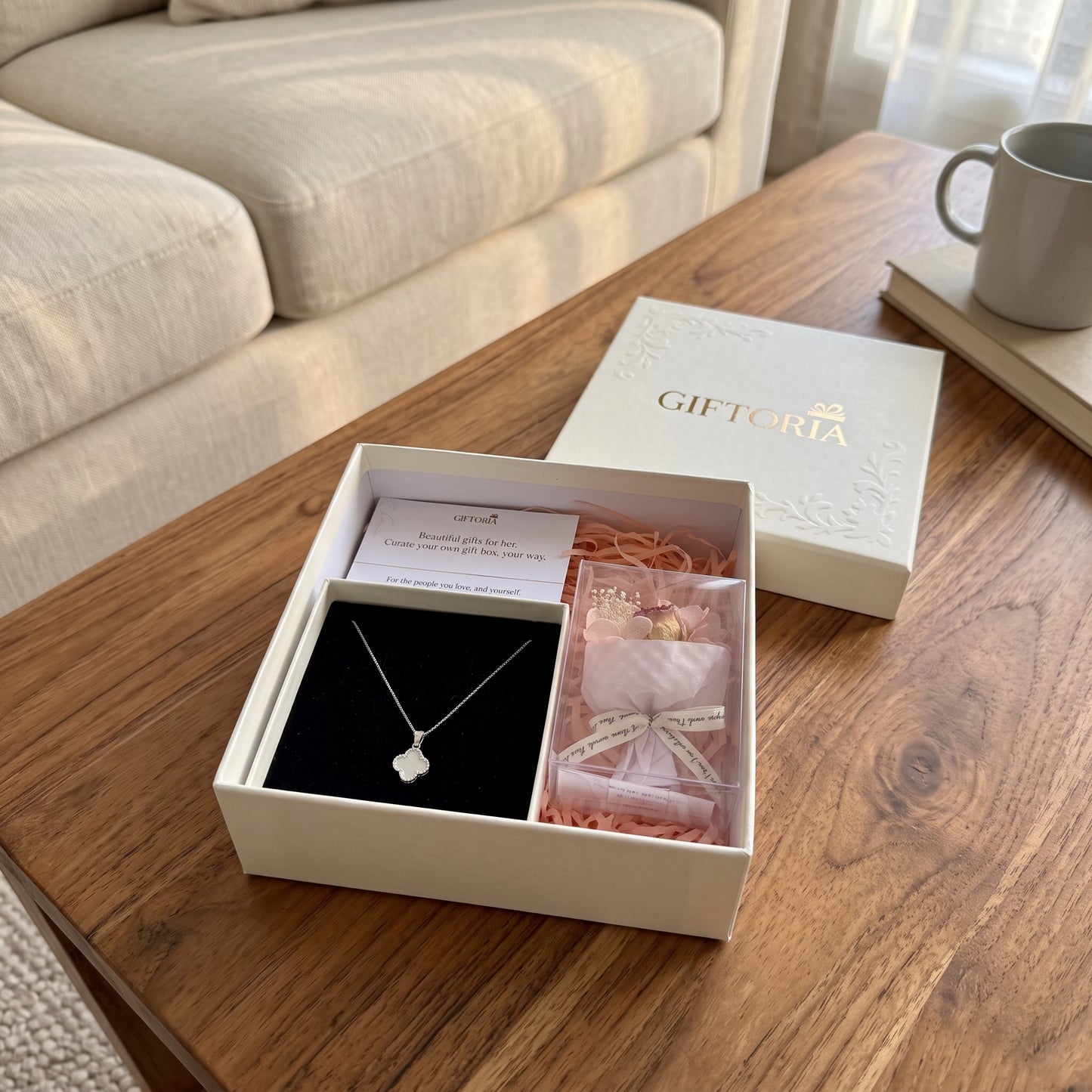 Sterling silver clover necklace and dried red rose gift set displayed in a bright living room