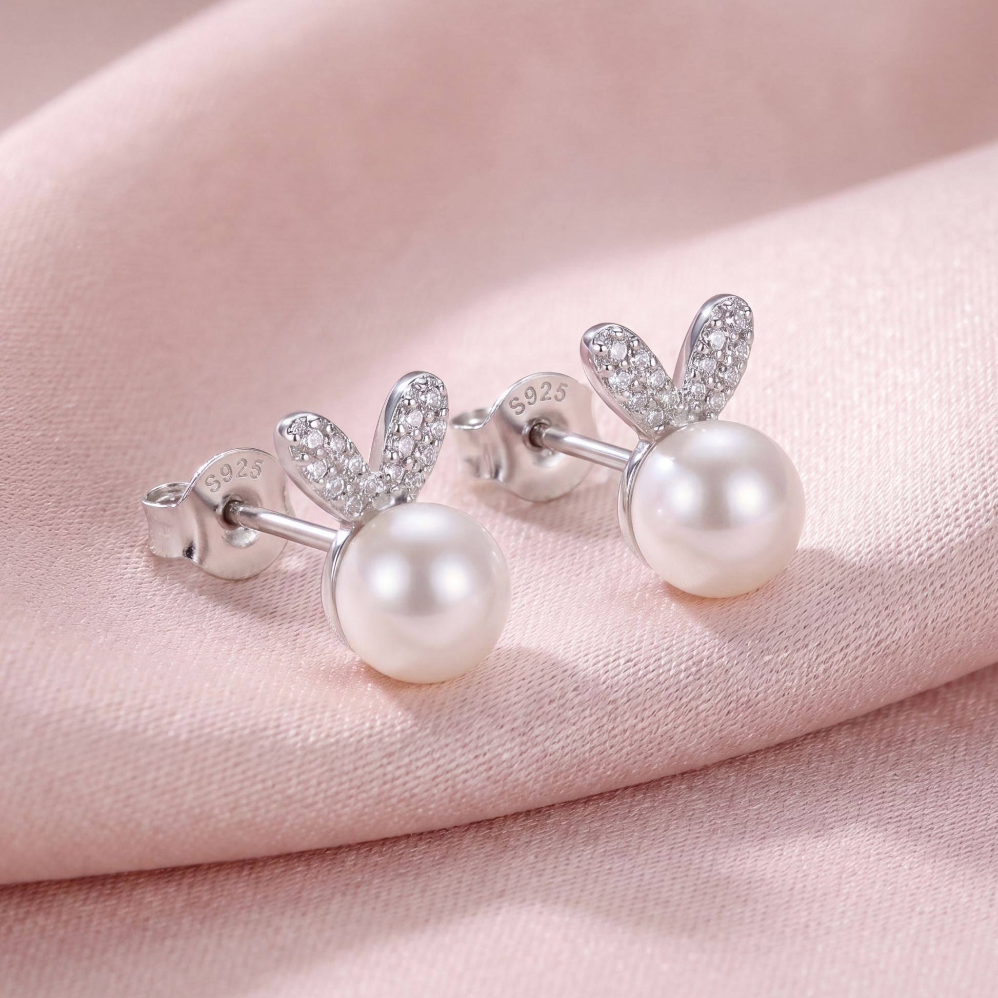 925 sterling silver pearl bunny stud earrings with polished silver ears and soft pearl accents on pink fabric
