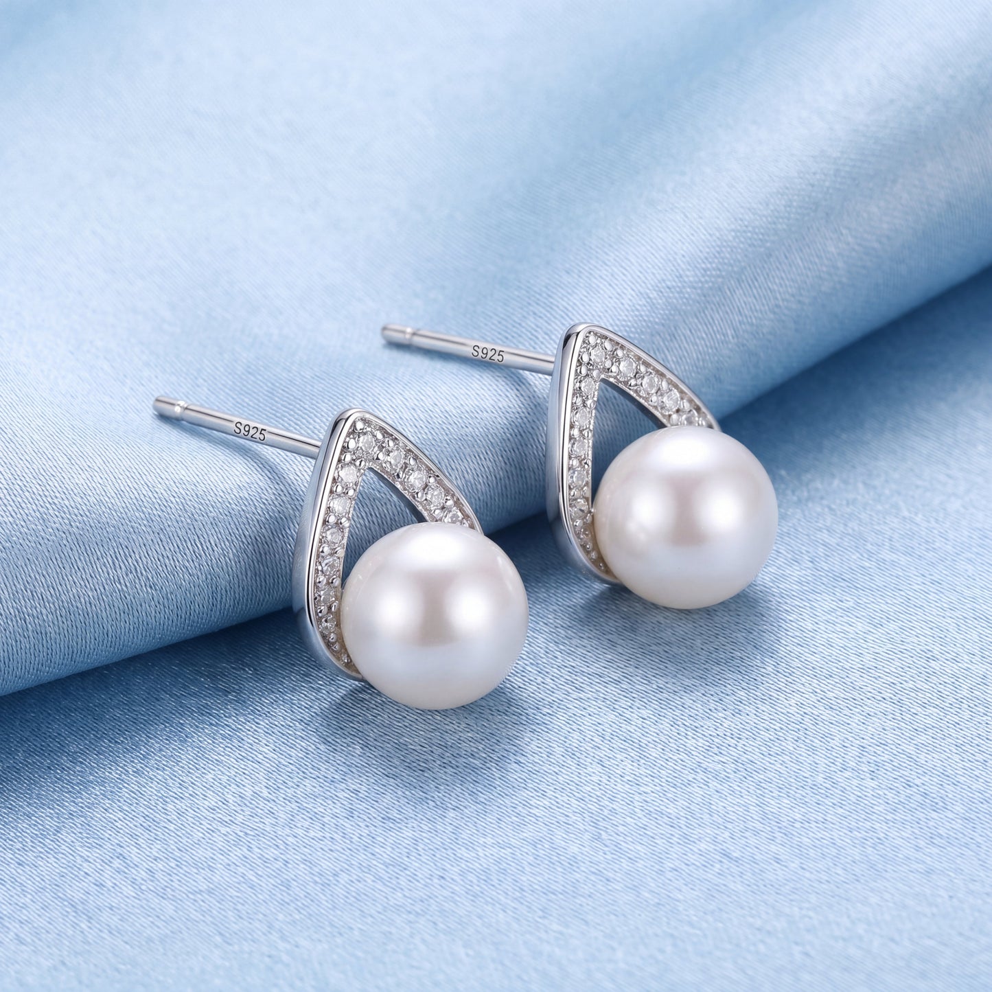 925 sterling silver pearl teardrop stud earrings with polished silver curves and soft white pearls on blue satin