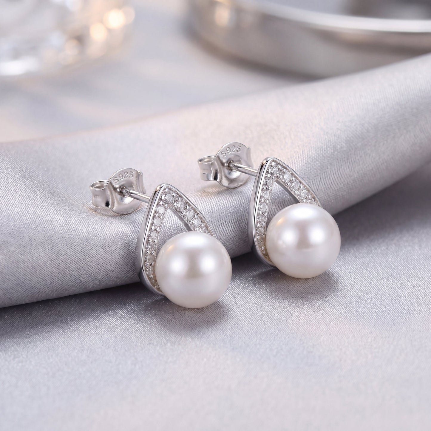 Elegant 925 sterling silver pearl teardrop stud earrings with sparkling silver detail and white pearls on soft fabric