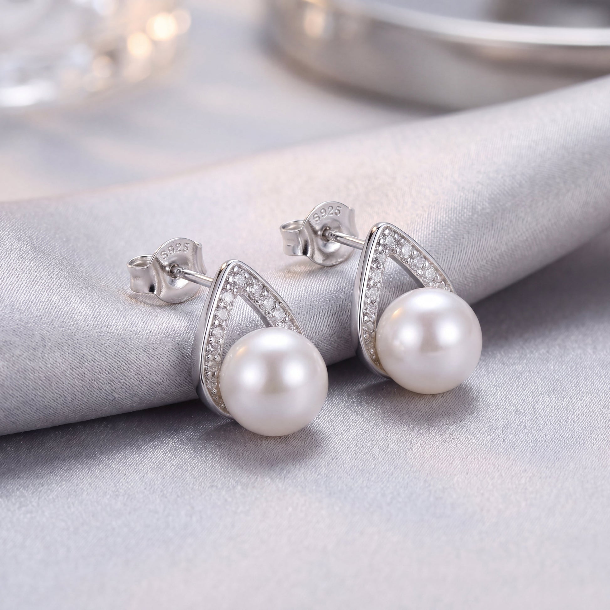 Elegant 925 sterling silver pearl teardrop stud earrings with sparkling silver detail and white pearls on soft fabric