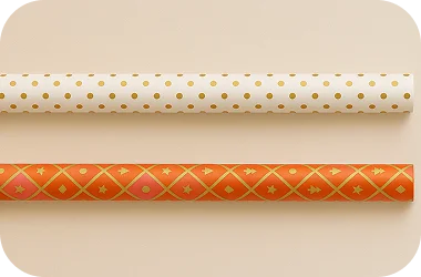 Two rolls of decorative paper with gold polka dots and orange pattern on a beige background
