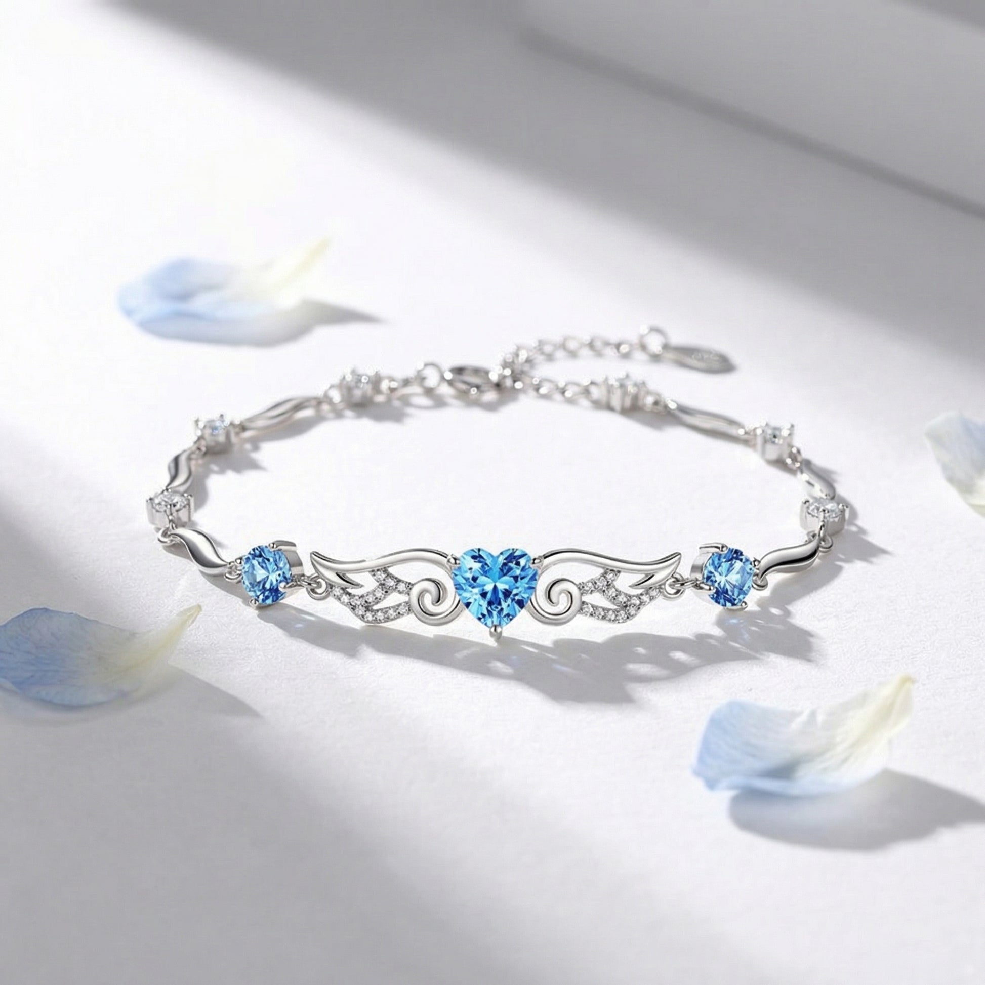 Angel Wings 925 sterling silver heart bracelet flat lay with blue heart crystal and elegant wing details