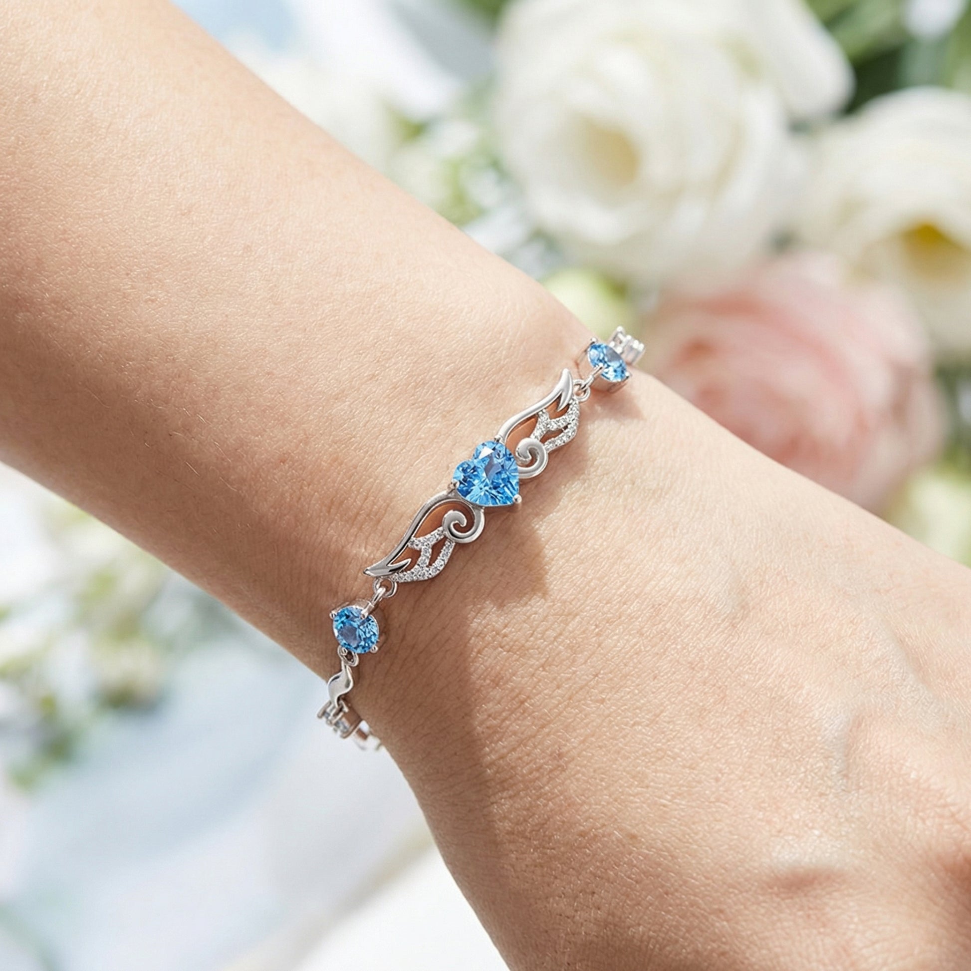 Angel Wings 925 sterling silver heart bracelet worn on wrist with blue heart crystal centre