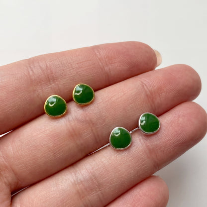 Avocado green stud earrings shown on hand to display small delicate size