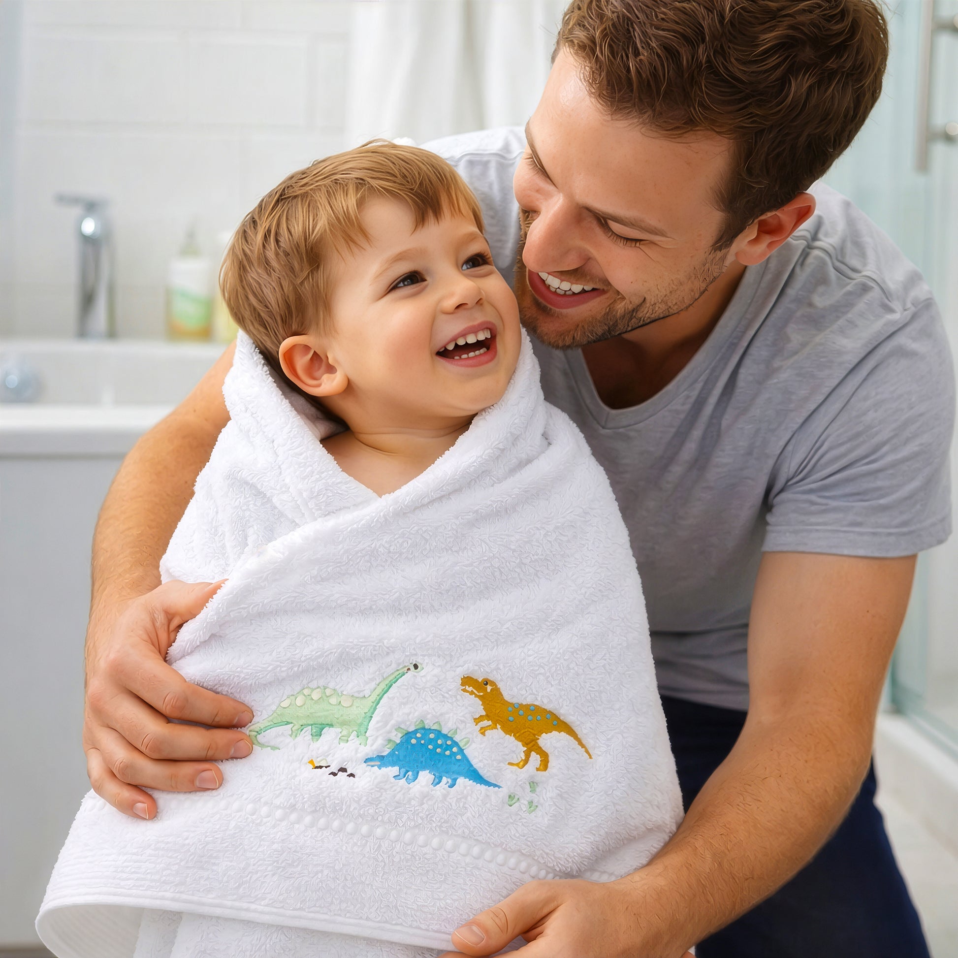 Father wrapping toddler in dinosaur baby bath towel from Giftoria Australia