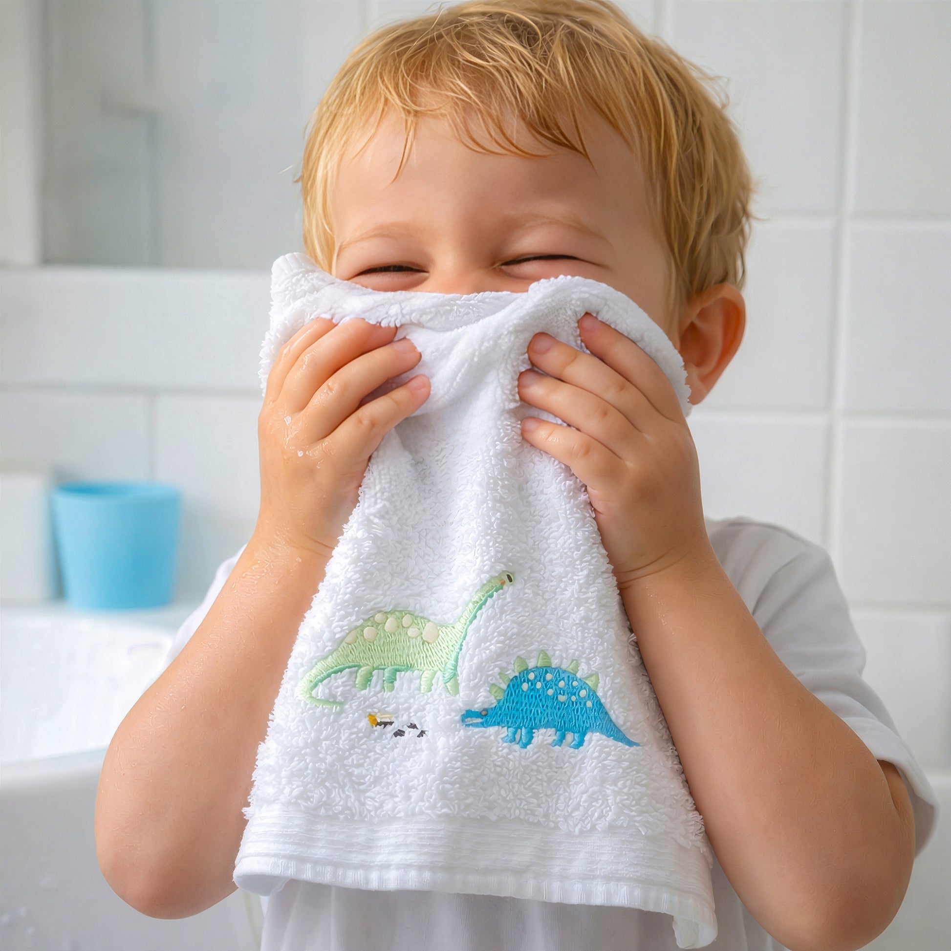 Baby using dinosaur embroidered face washer from bath gift set