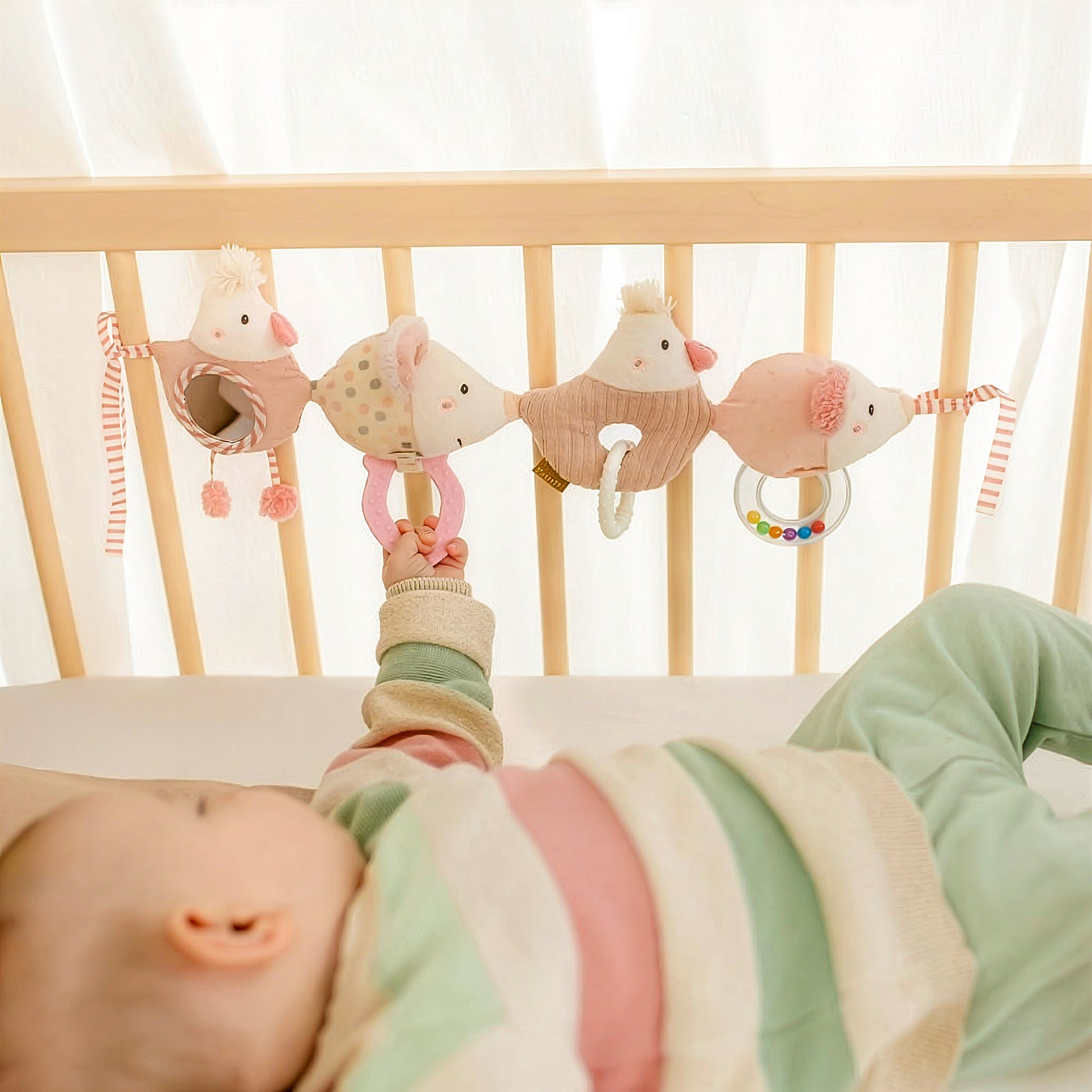 Baby reaching for fairy pram chain toy with teether and rattle