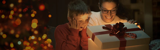 Woman and child opening a Christmas gift with festive lights in the background