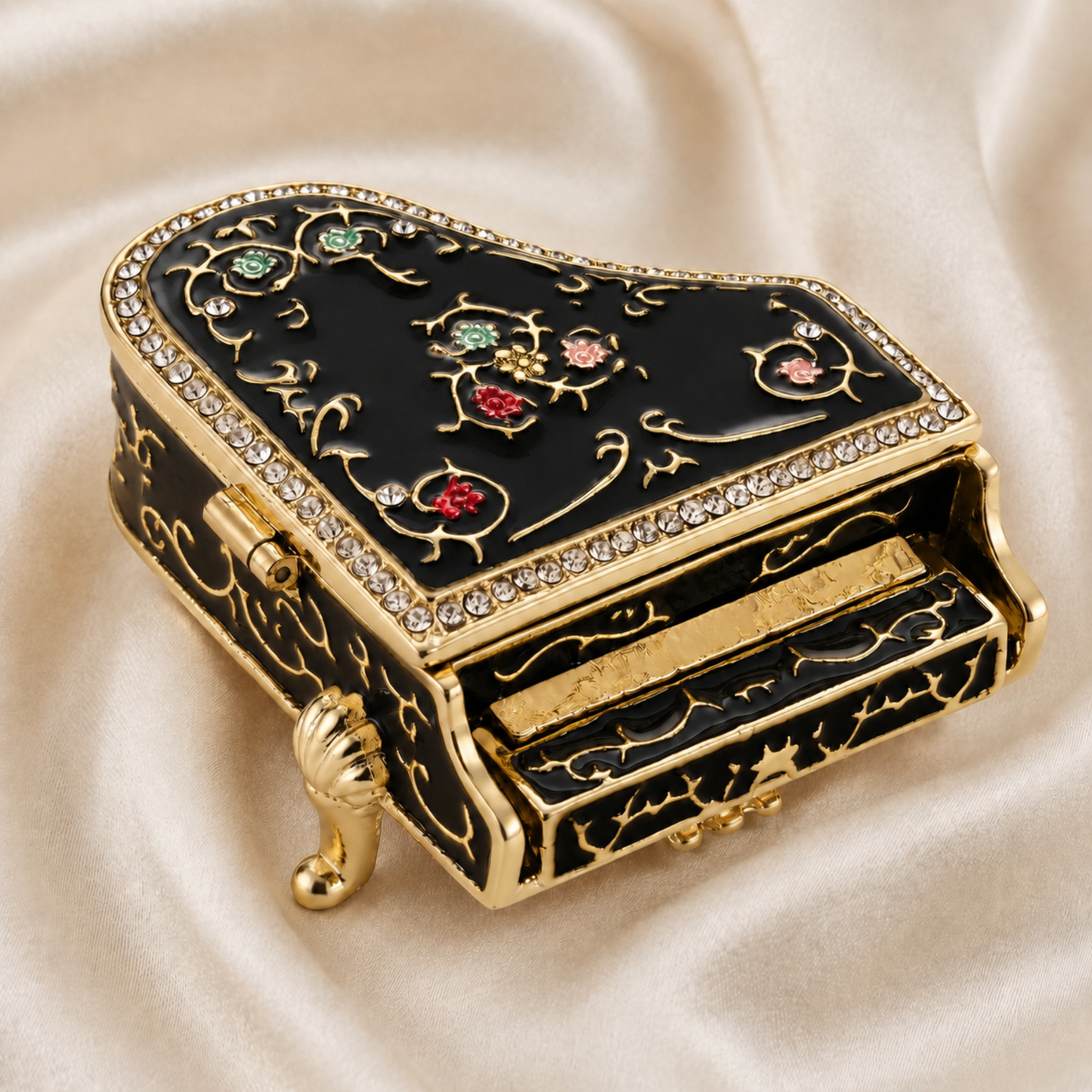 Black floral grand piano jewellery box, displayed on a cream satin fabric background.