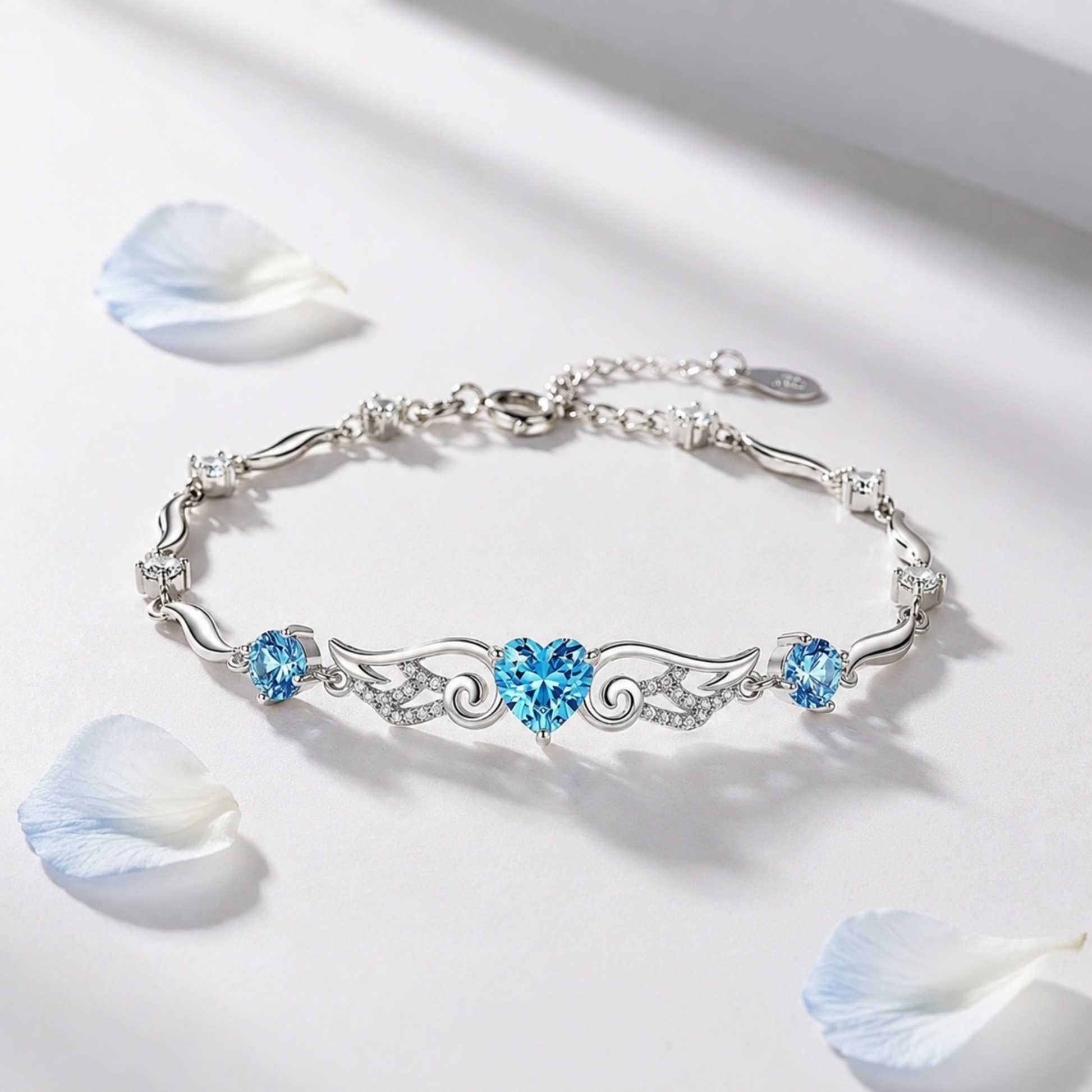 Blue angel wings heart bracelet in sterling silver displayed with white flower petals