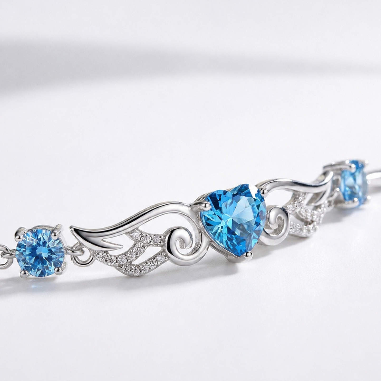 Close-up of blue heart cubic zirconia and angel wing details on a silver bracelet