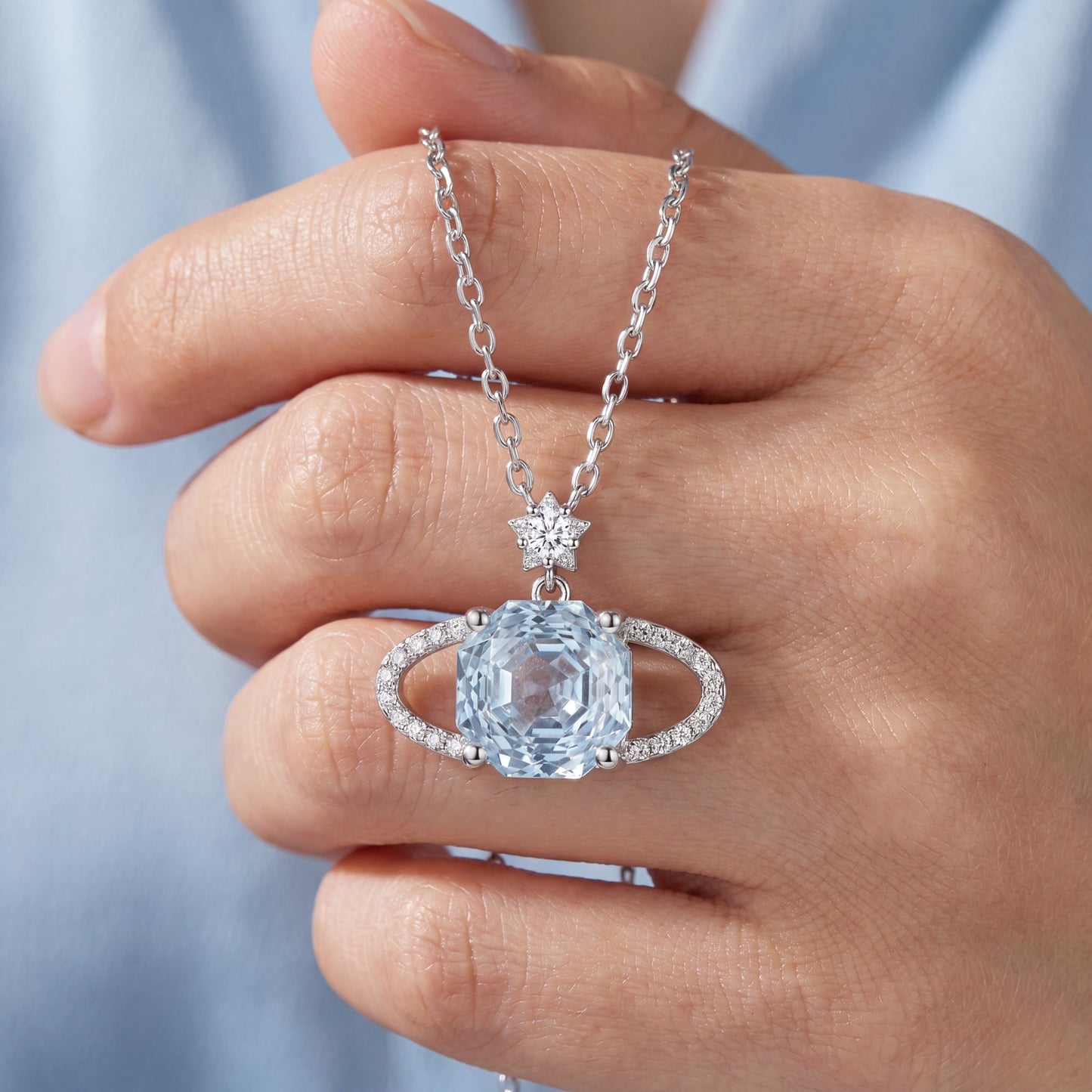 Blue planet sparkling star necklace held by hand showing pendant detail and chain