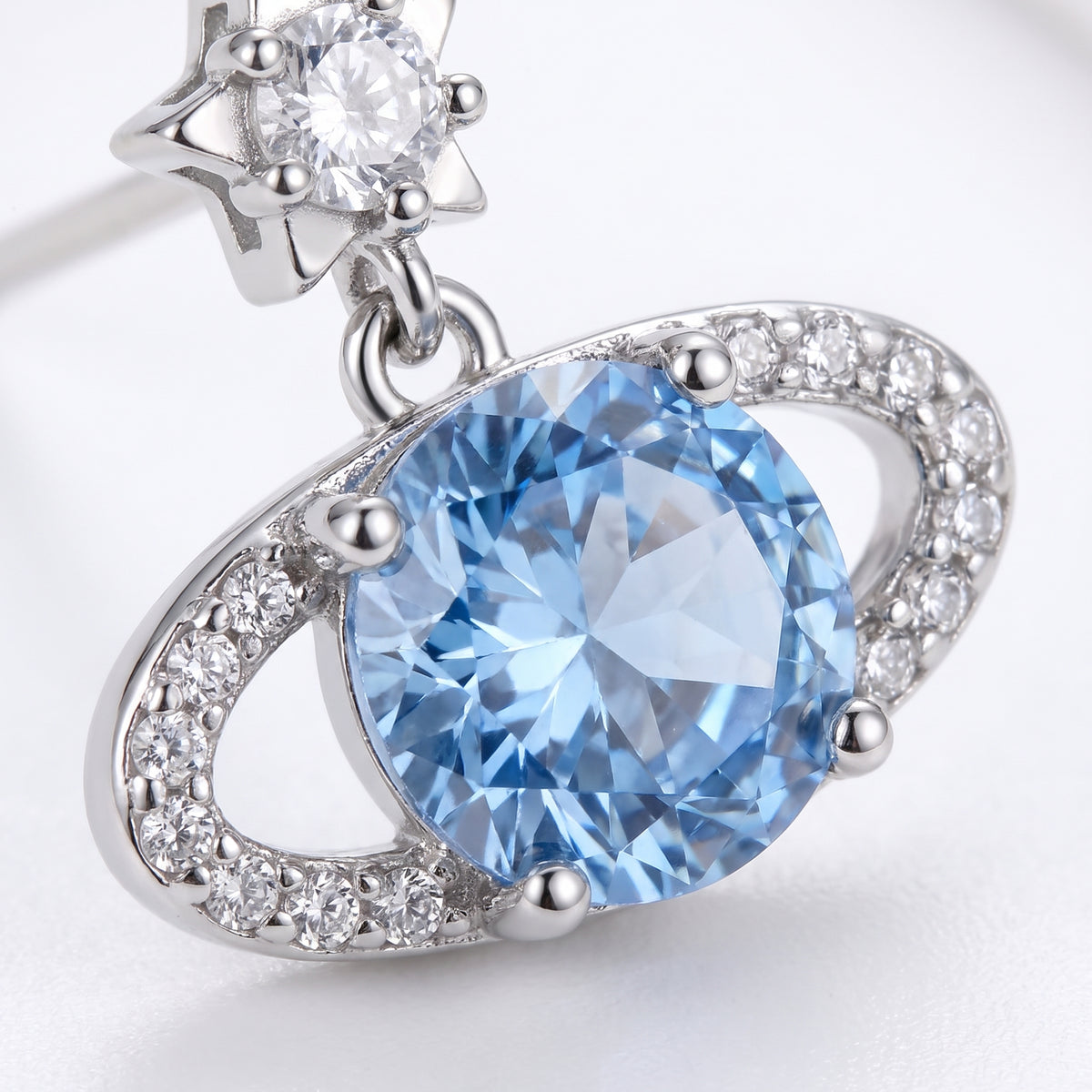 Close-up of a Blue Rose Saturn silver stud earring showing the faceted blue centre stone and surrounding clear stones.