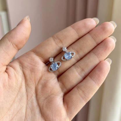 Pair of Blue Rose Saturn silver stud earrings resting on a palm to show their scale.