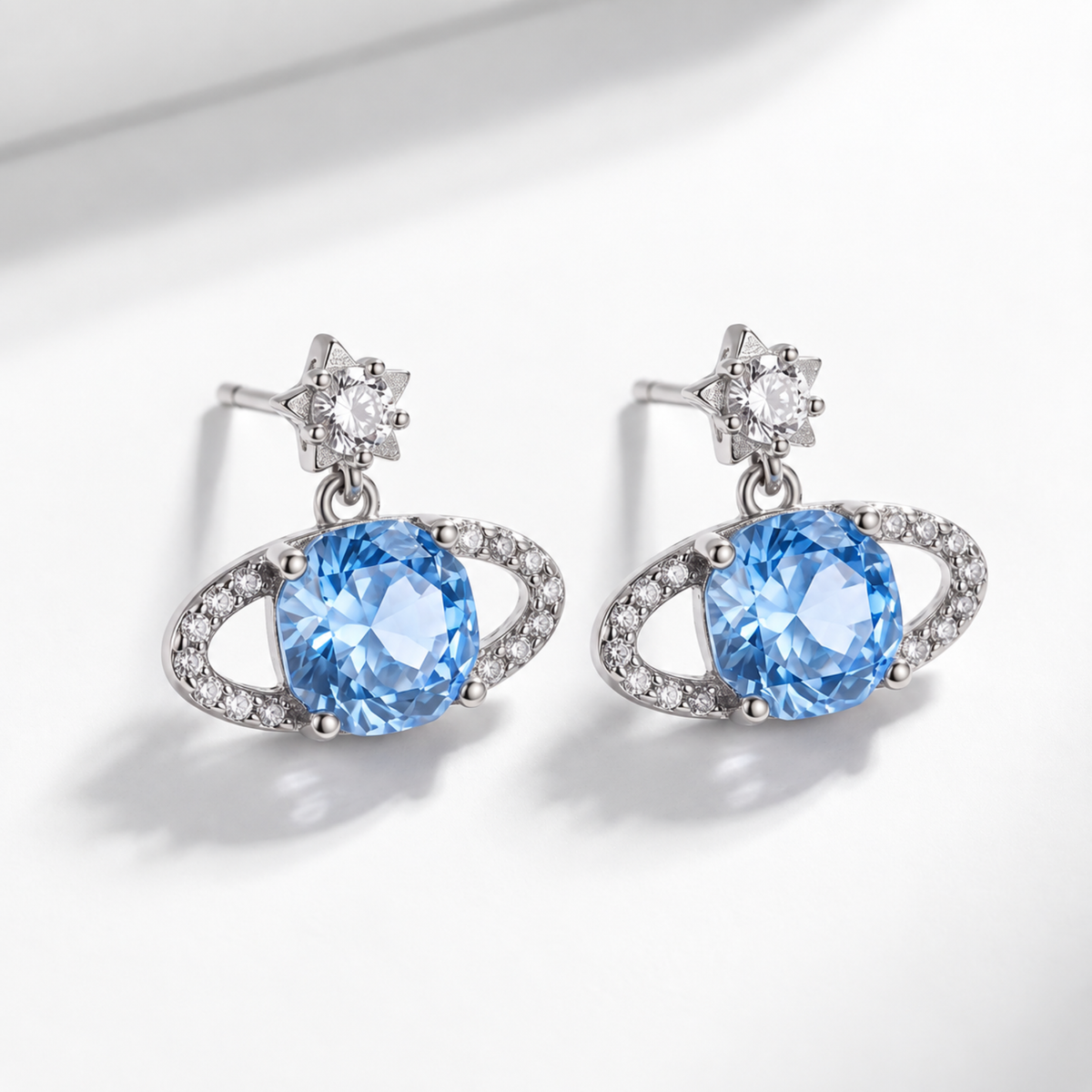 Blue Rose Saturn silver stud earrings viewed at an angle on a light background with soft shadows.