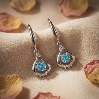 Blue sterling silver teardrop dancing crystal earrings on soft fabric with sparkling detail
