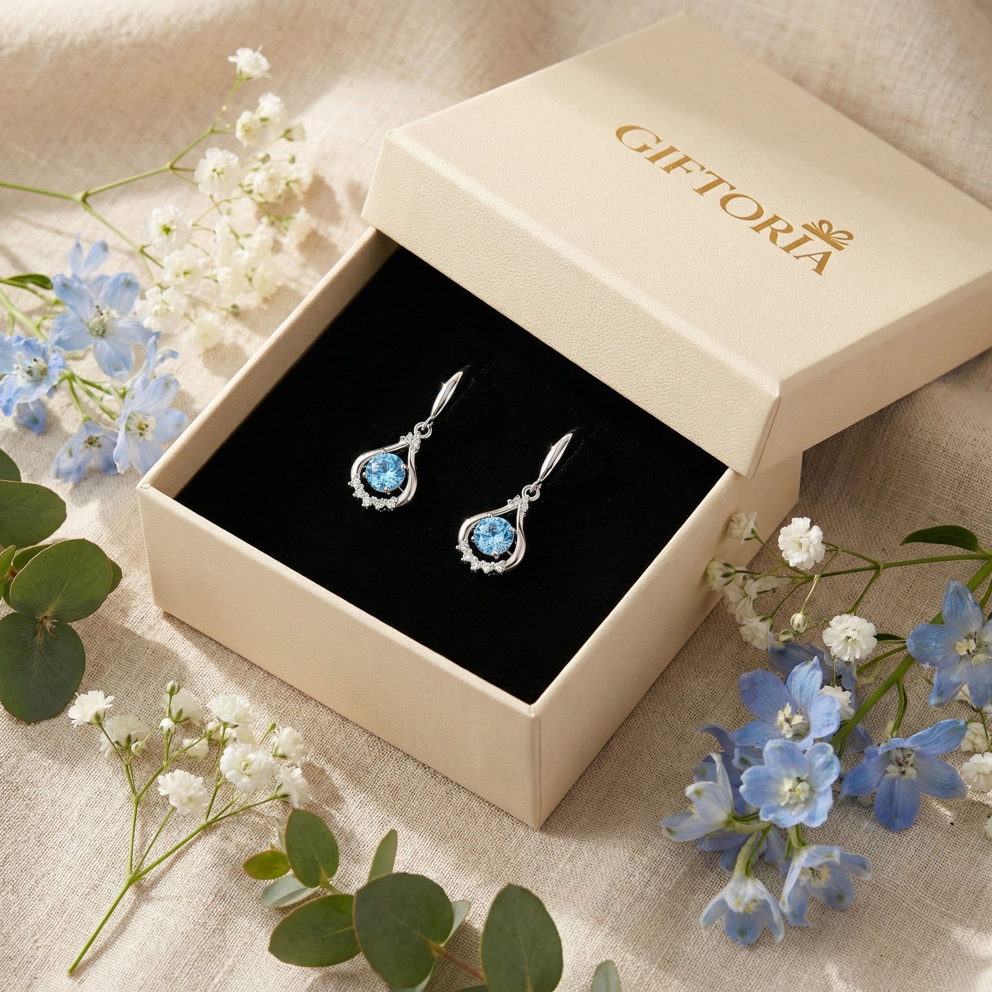 Blue teardrop dancing cubic zirconia earrings presented in a Giftoria gift box