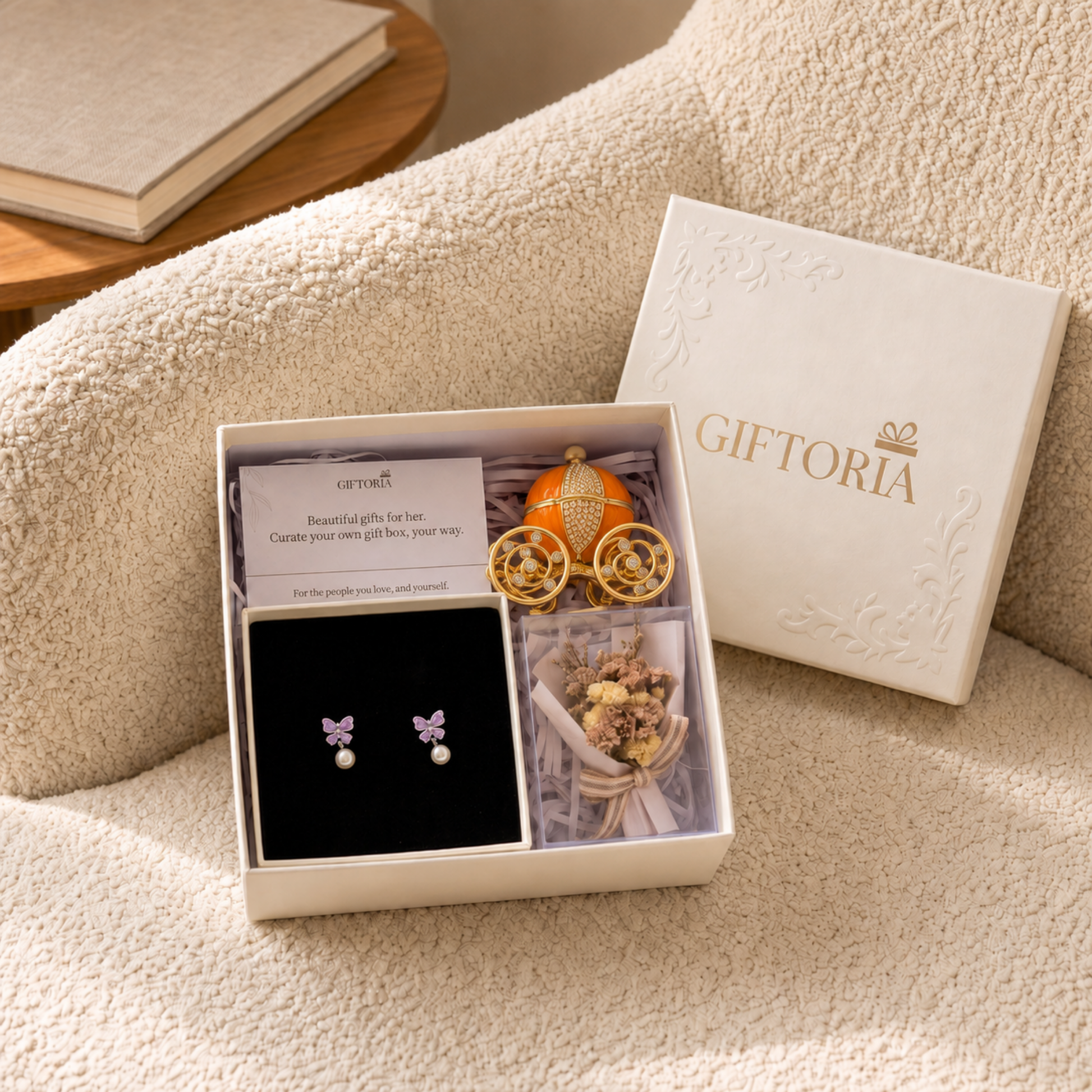 Butterfly earrings, dried flowers and carriage jewellery box gift set styled on a cream sofa