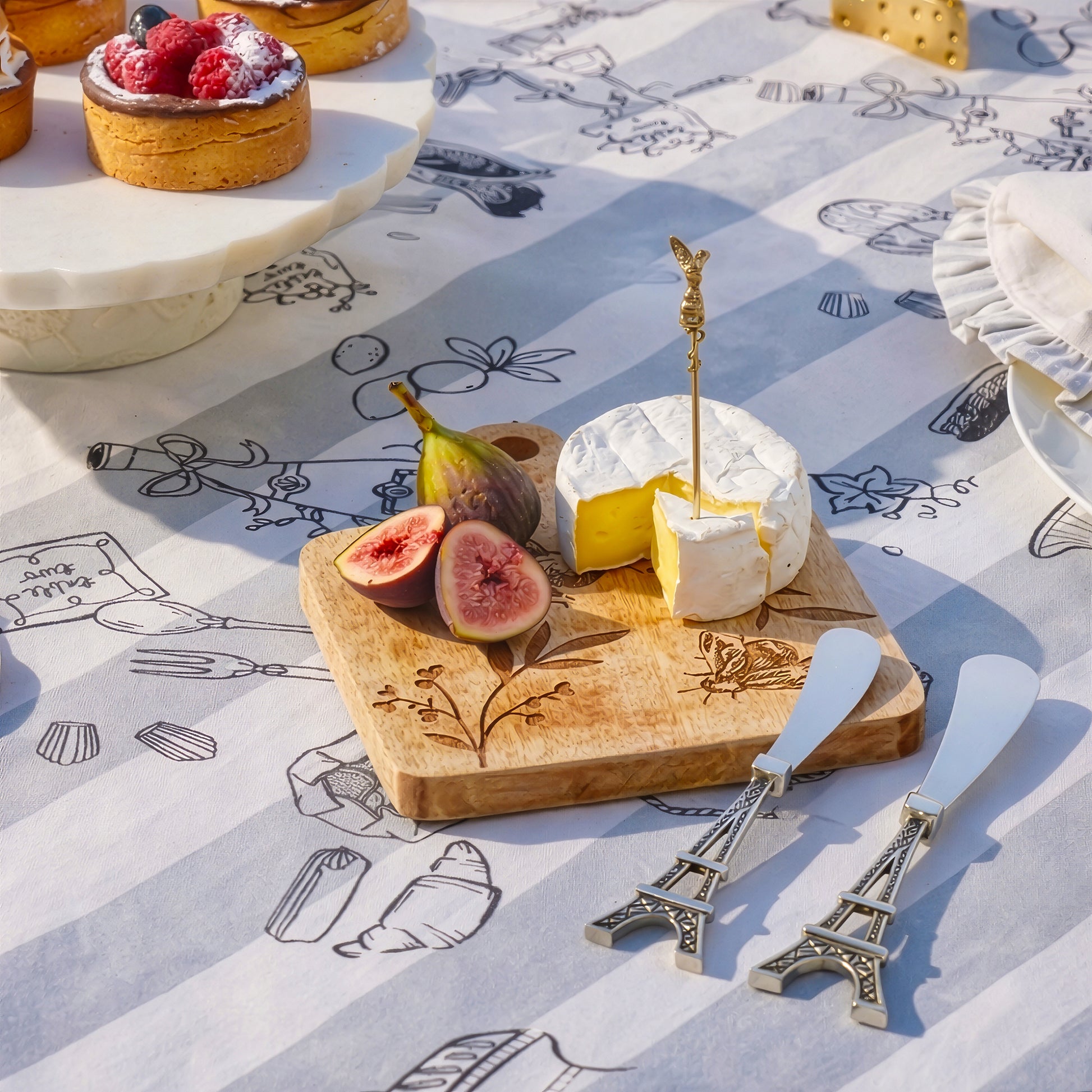 Cheese spreader set displayed on picnic serving board with cheese and figs