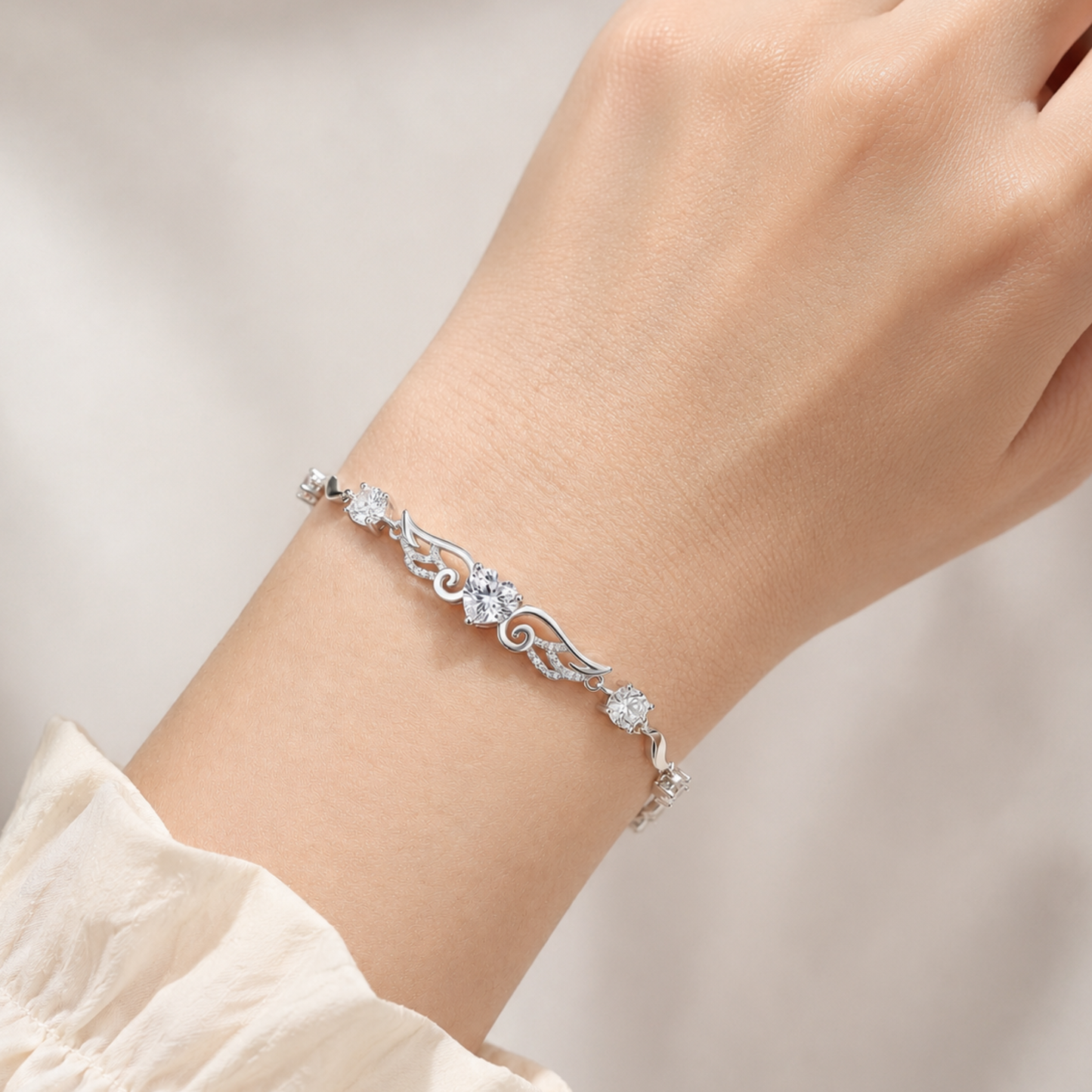Clear cubic zirconia angel wings heart bracelet worn on a woman’s wrist