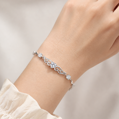 Clear cubic zirconia angel wings heart bracelet worn on a woman’s wrist