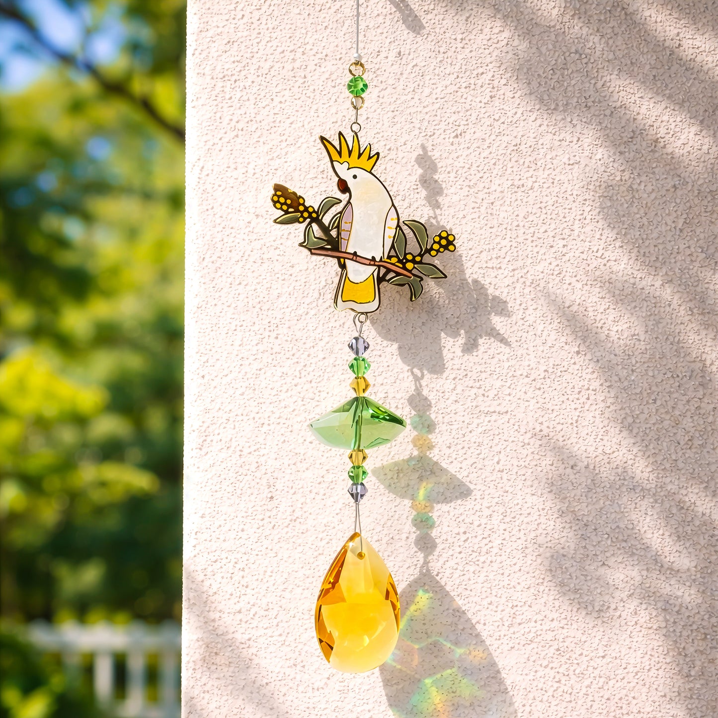 Crystal sun catcher with cockatoo design casting colourful light reflections on wall