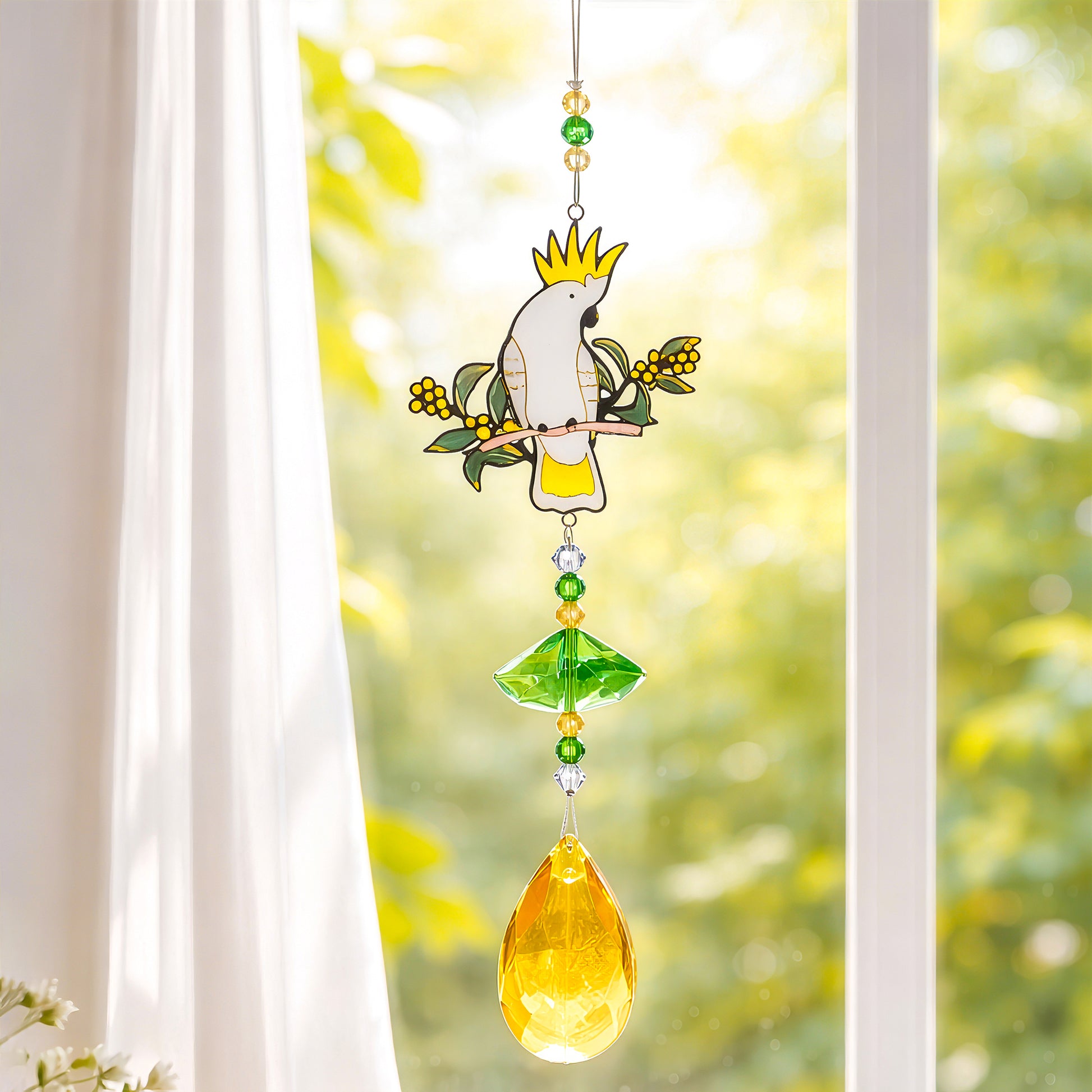 Crystal sun catcher bird with cockatoo design hanging in window, reflecting rainbow light for home decor