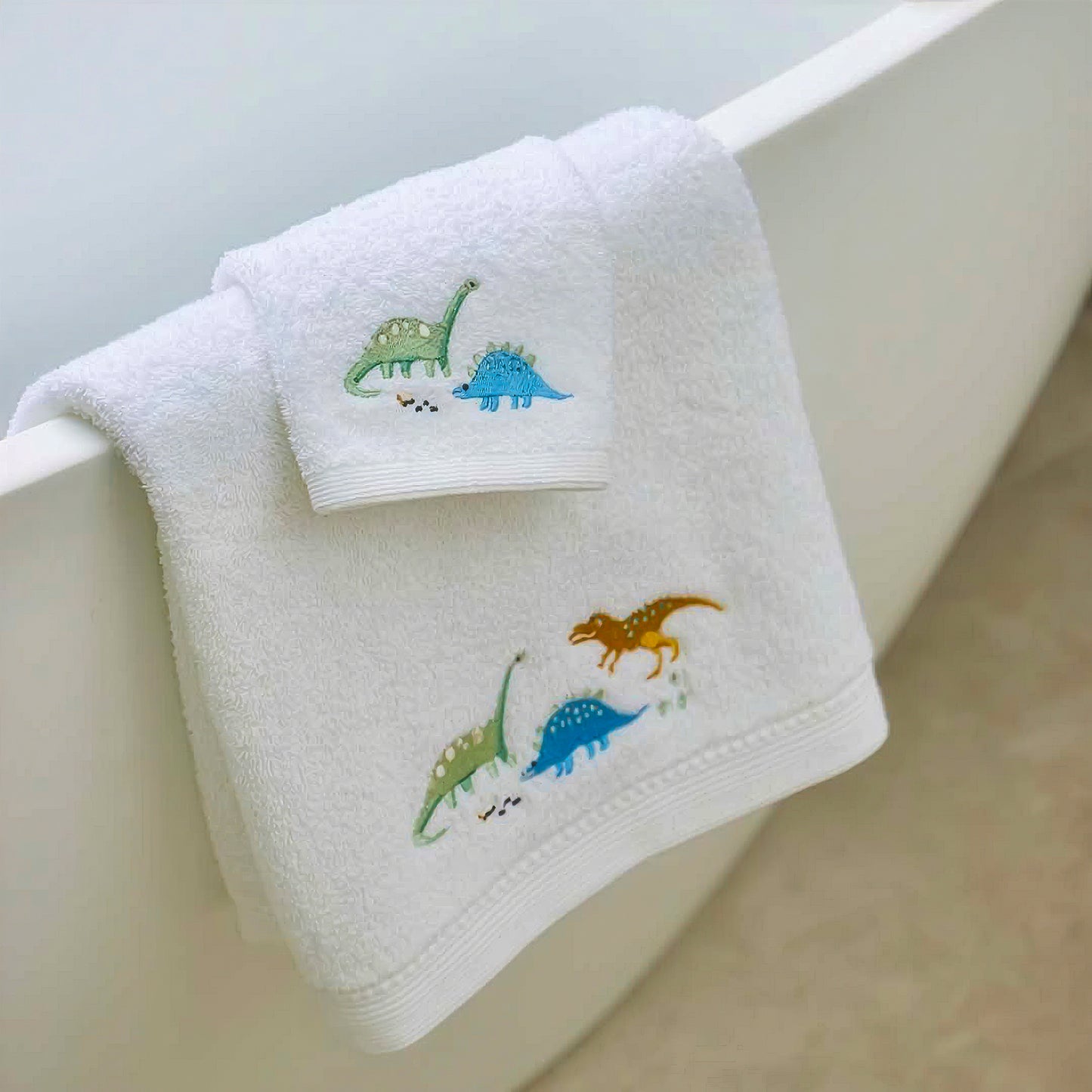 Dinosaur baby bath towel and face washer hanging by bathtub