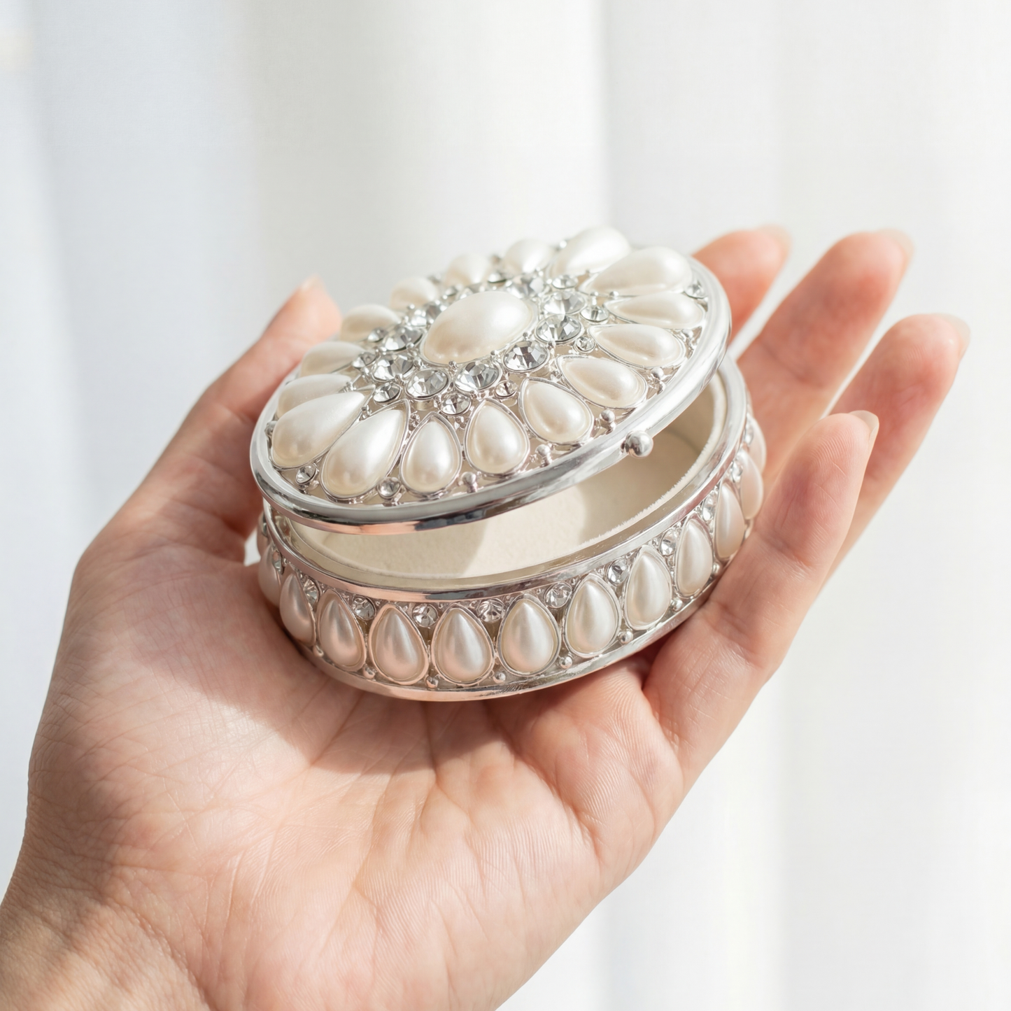 Elegant Pearl Oval Jewellery Box held in hand to show its compact size and delicate design