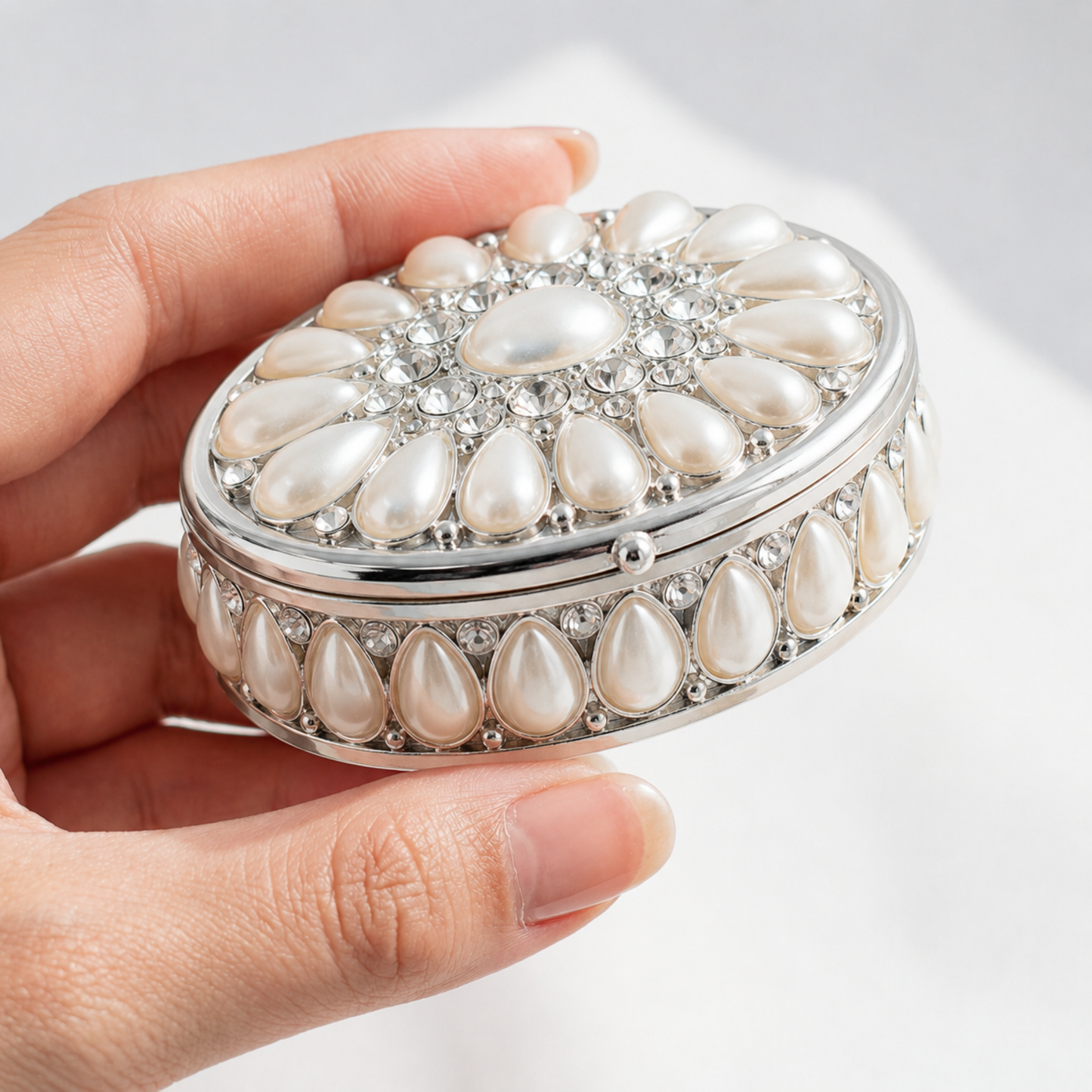Elegant Pearl Oval Jewellery Box held in hand to show its compact size and delicate design