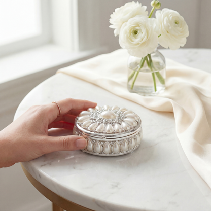 Elegant Pearl Oval Jewellery Box on a table in a soft lifestyle setting with a hand reaching toward it