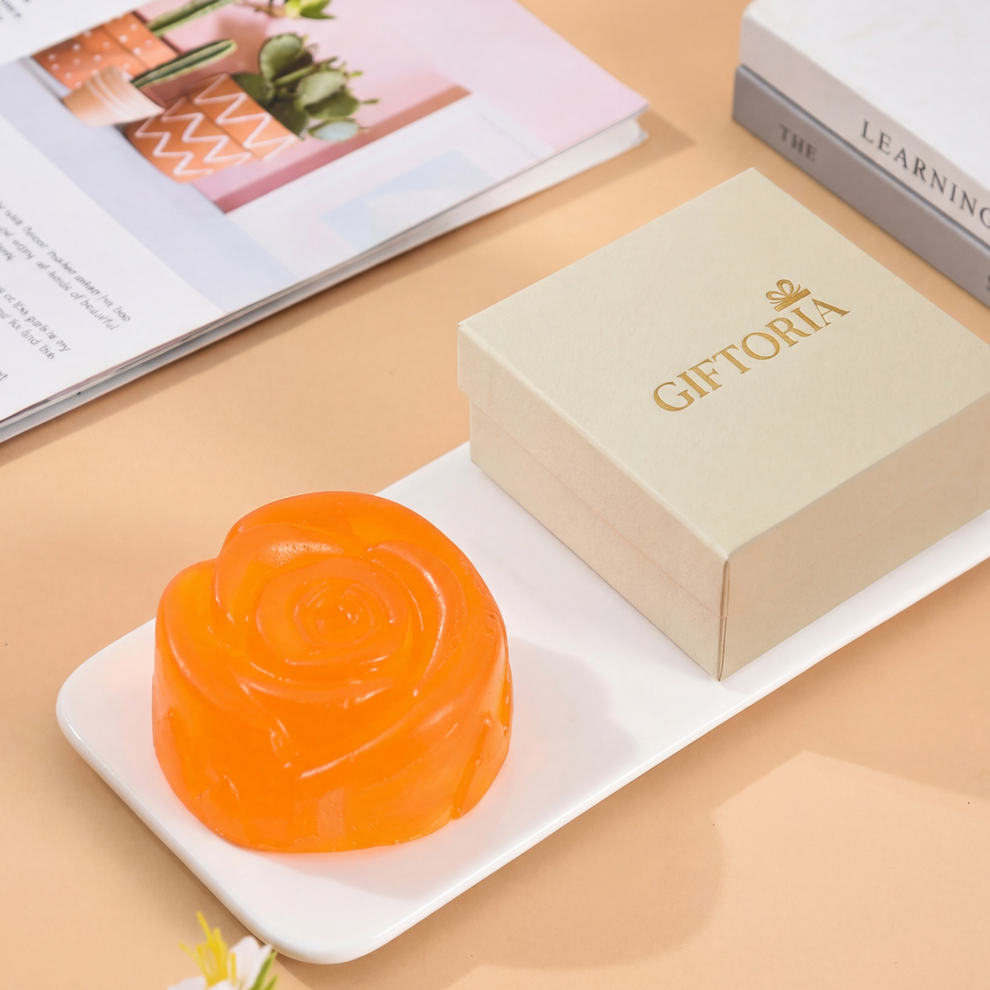 Gift-ready handmade floral essential oil soap in orange honey shape beside Giftoria gift box.
