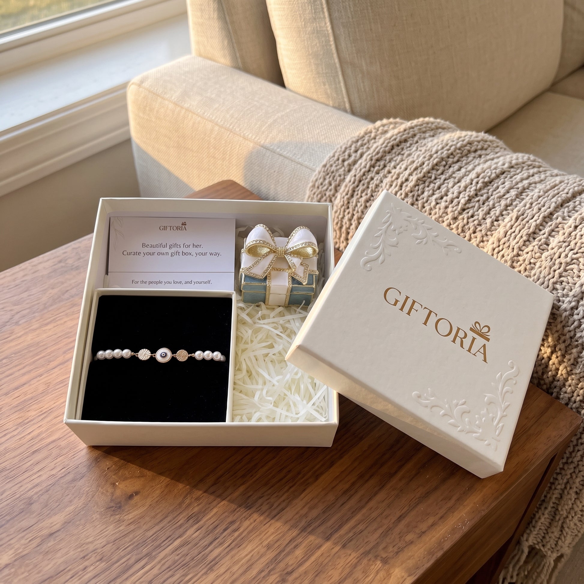Giftoria evil eye pearl bracelet and vintage bow jewellery box gift set displayed beside an armchair