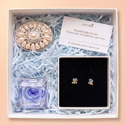 Open Giftoria gift box with gold butterfly earrings, a blue preserved rose and pearl jewellery box