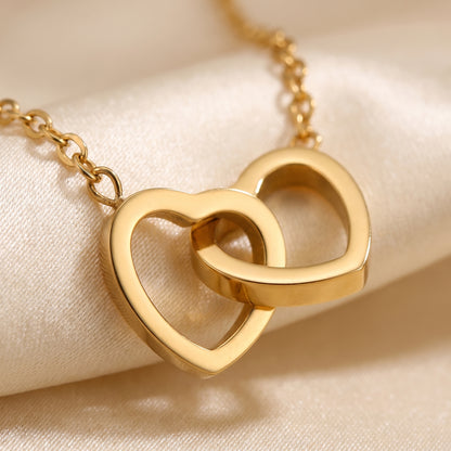 Close-up of the polished gold double linked heart pendant showing its interlocking design and smooth finish