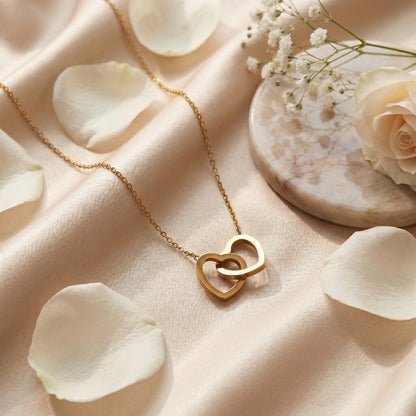 Gold double linked heart necklace arranged with white flower petals for a romantic anniversary gift