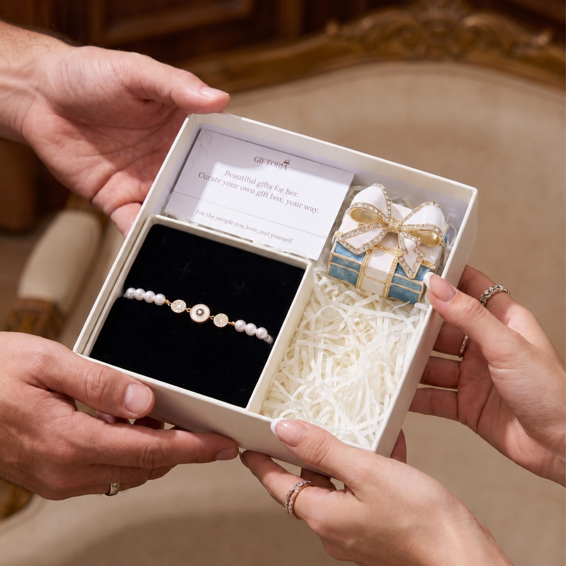 Hands holding an open gift set with a gold evil eye pearl bracelet and bow jewellery box
