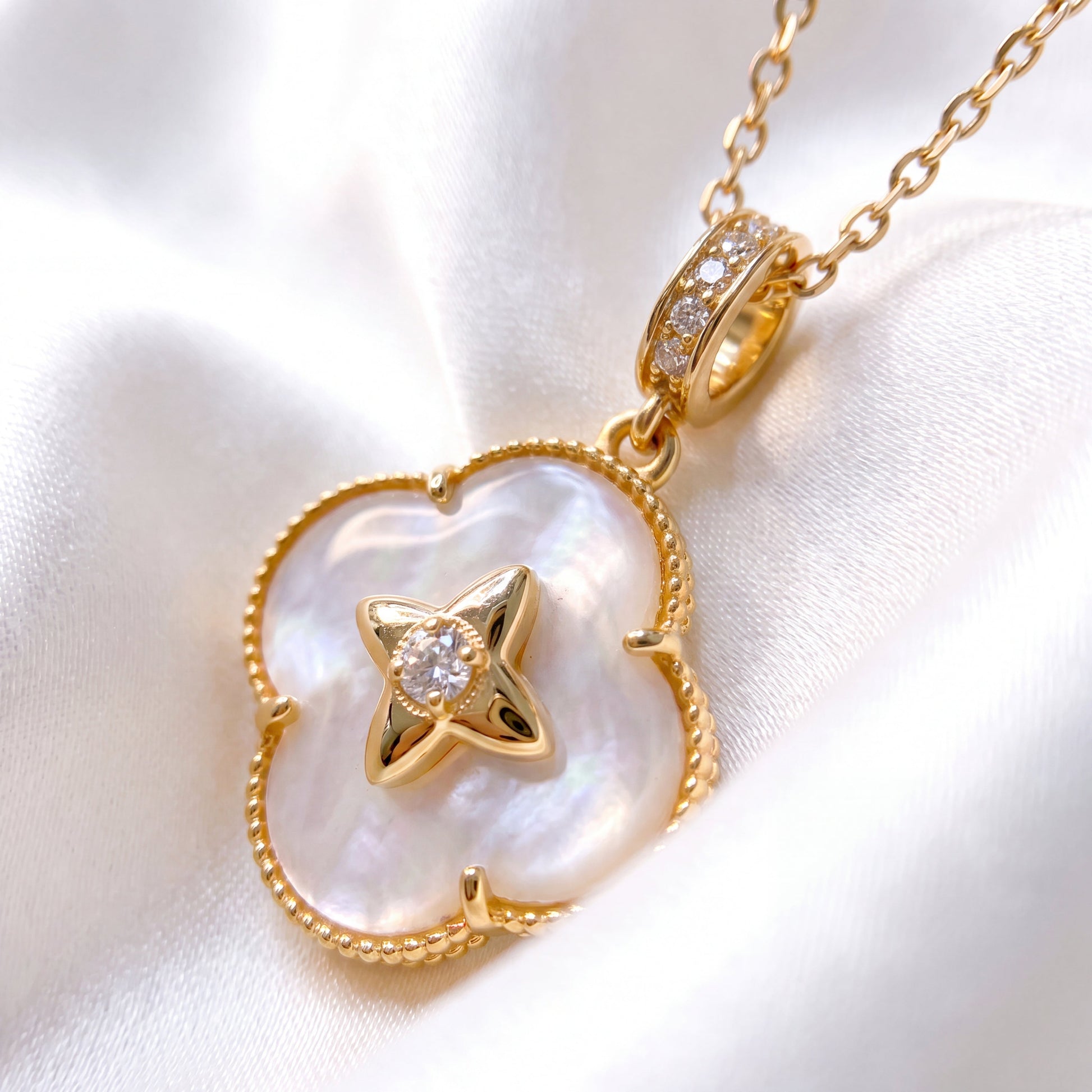 Gold mother of pearl clover pendant necklace displayed on white satin