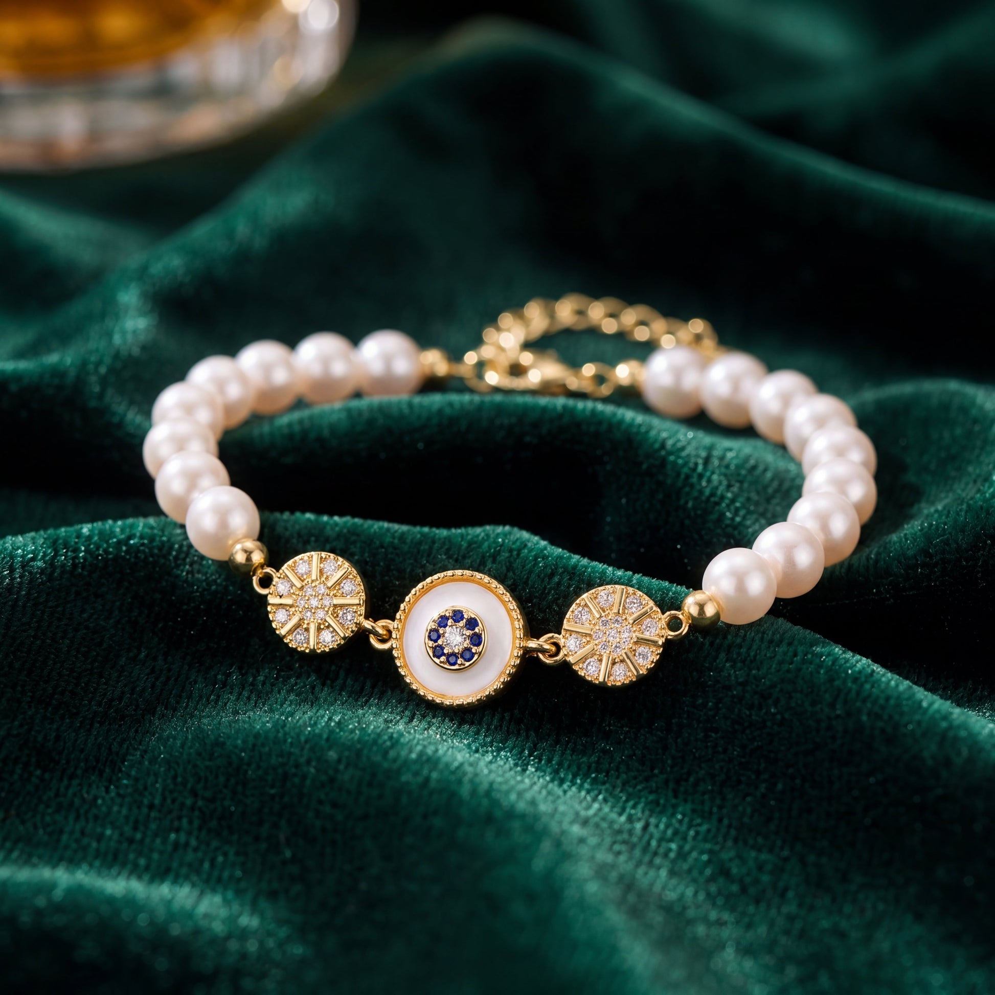 Gold Sunburst Evil Eye Pearl Bracelet displayed on rich green velvet