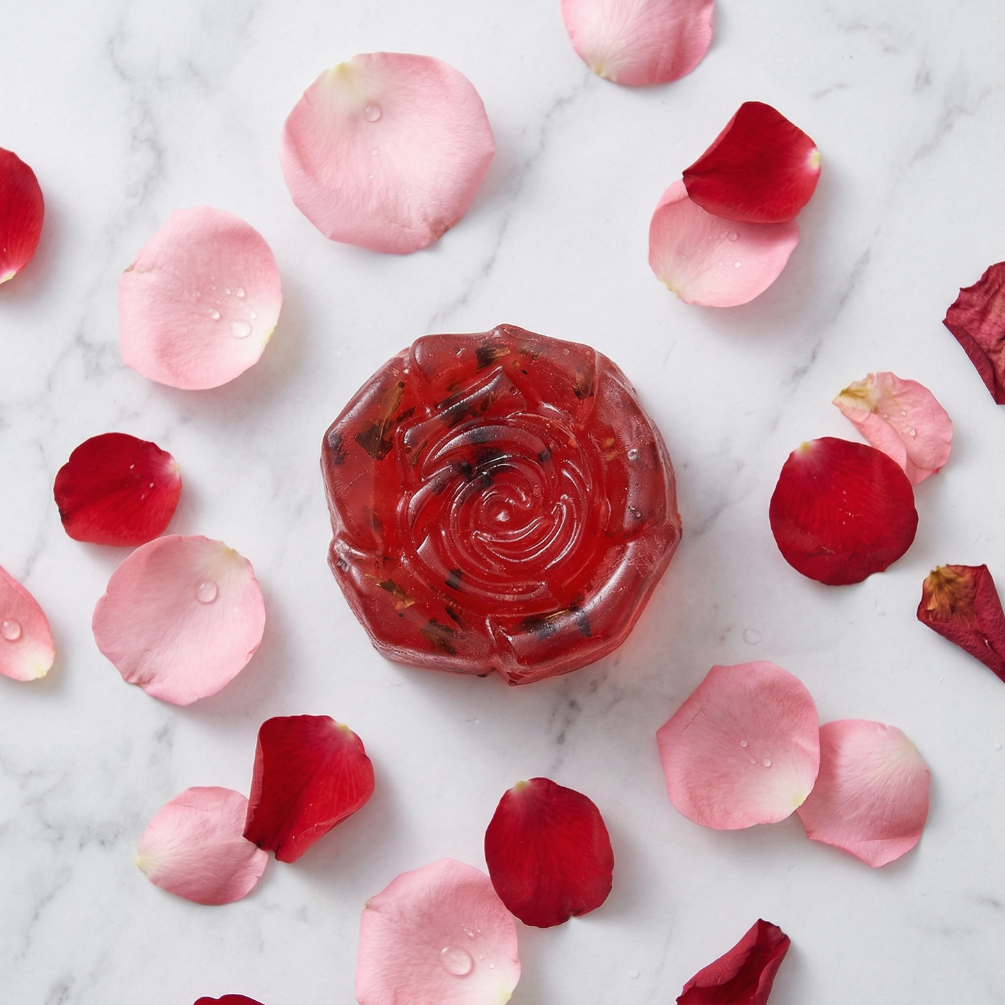Handmade floral essential oil soap in red rose shape styled with scattered rose petals.