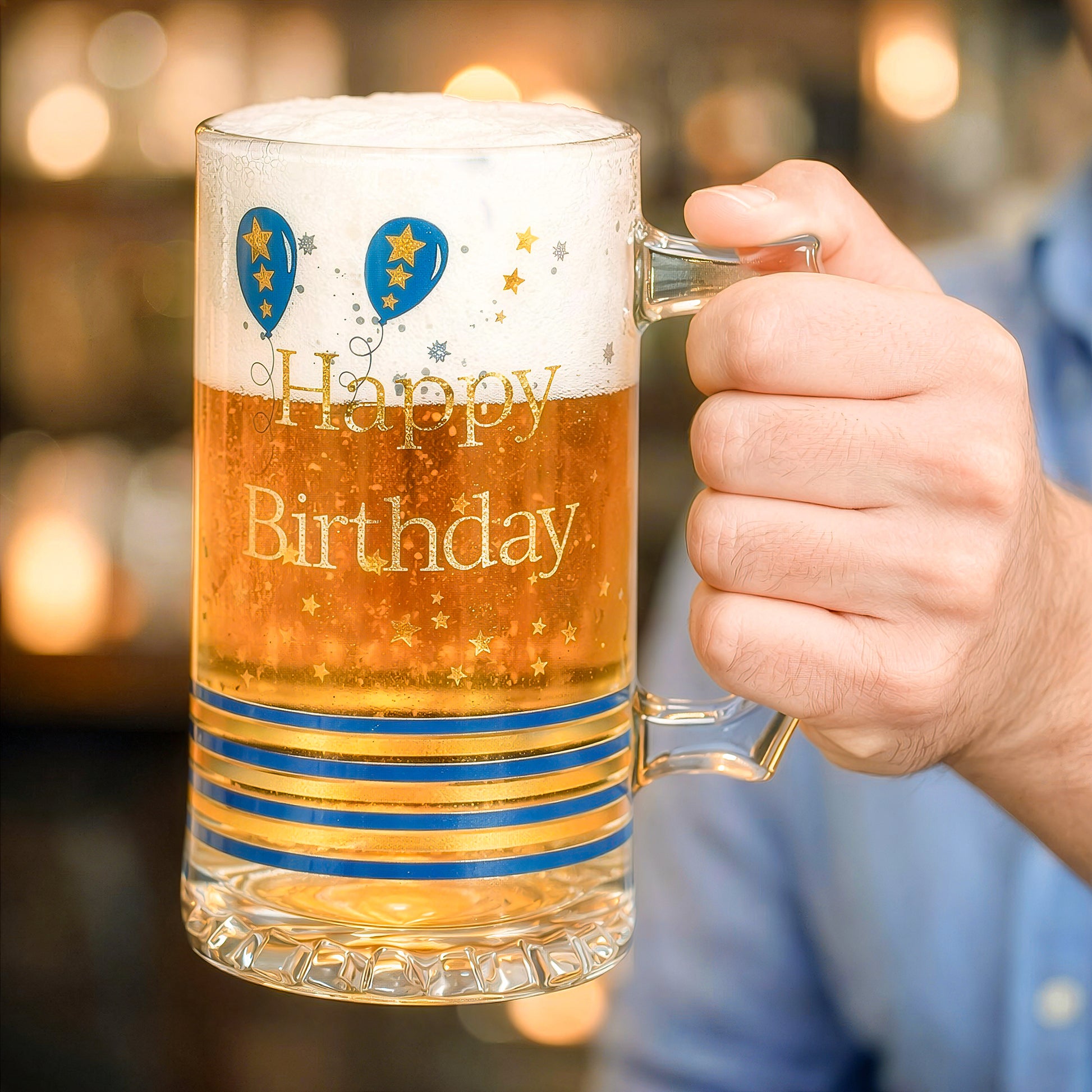 Hand holding a happy birthday beer tankard mug filled with beer