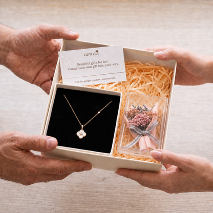 Hands presenting a lucky clover necklace and pink dried flower gift set for her