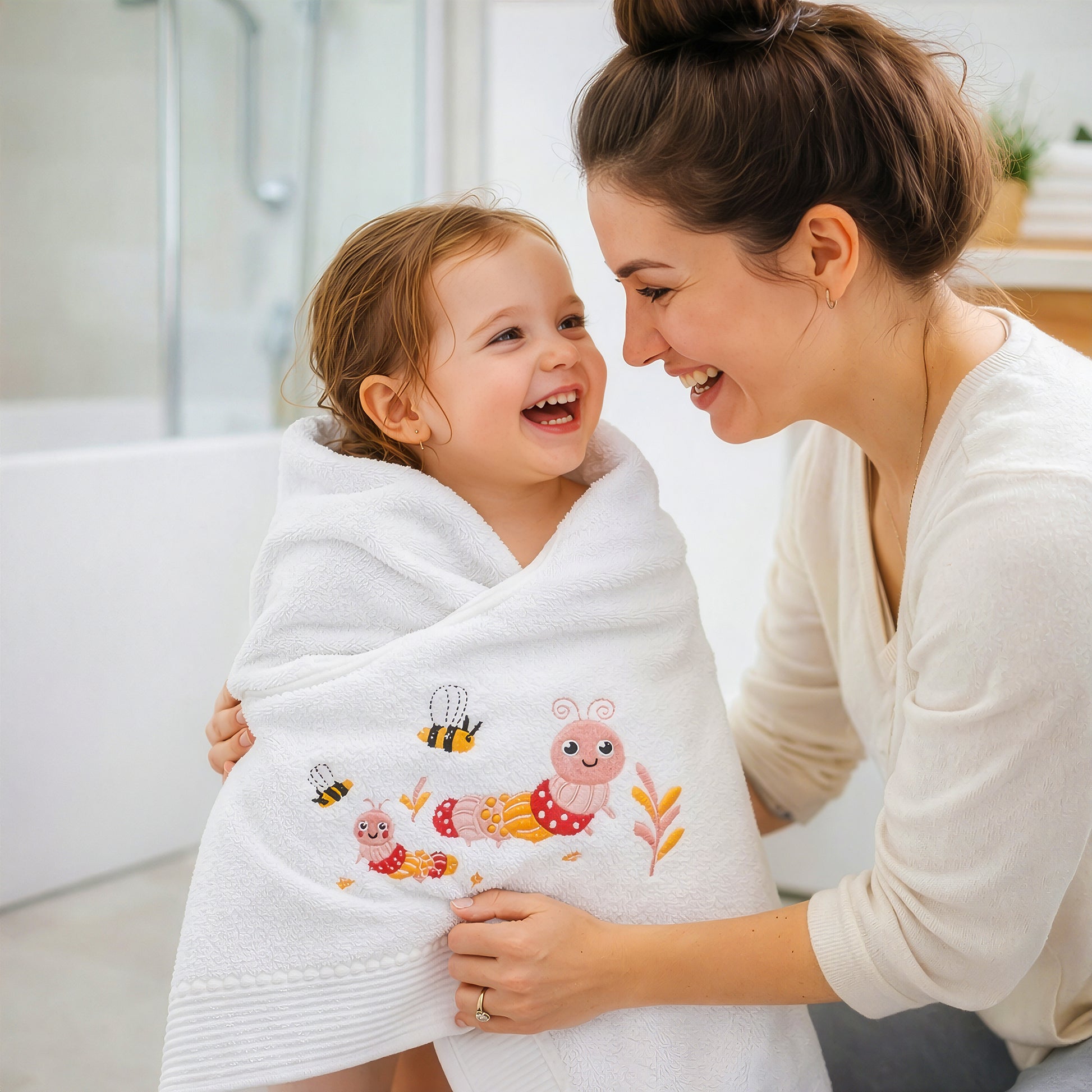 Mother wrapping toddler in soft pink baby bath towel