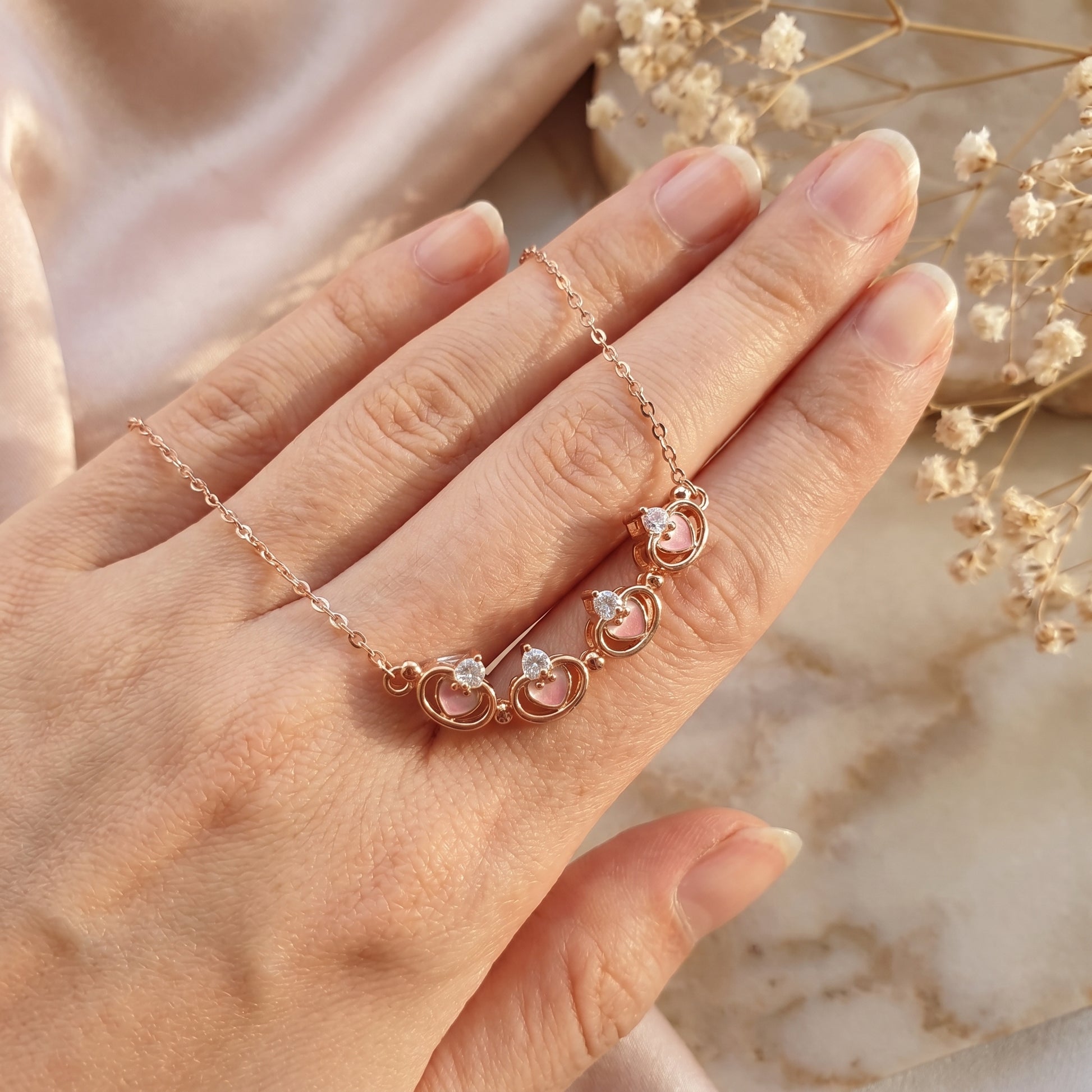 Open rose gold magnetic clover necklace shown on hand