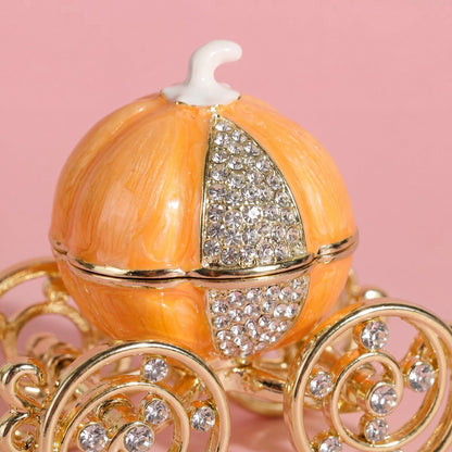 Close up of orange pumpkin carriage jewellery box with sparkling crystal-style panels and elegant gold wheel details.