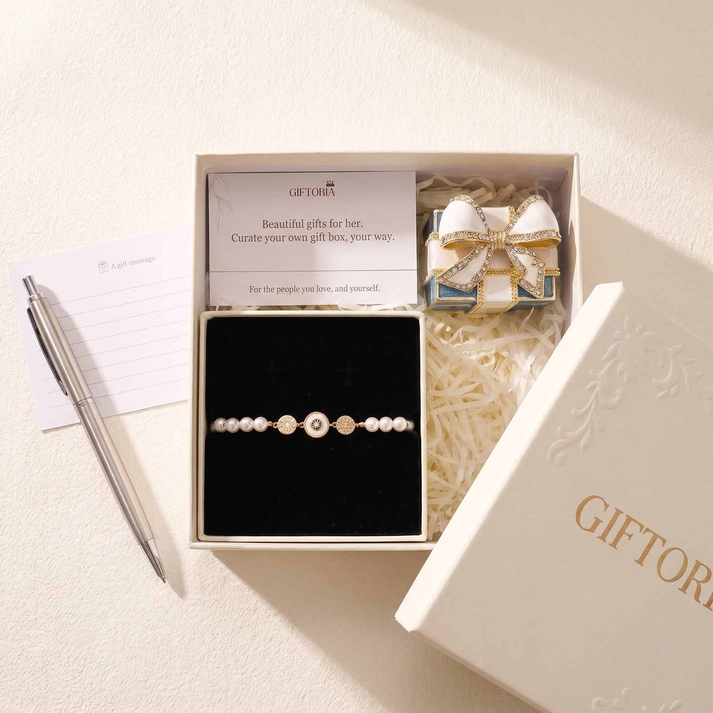 Gold evil eye pearl bracelet gift set beside a personal message card and Giftoria gift box
