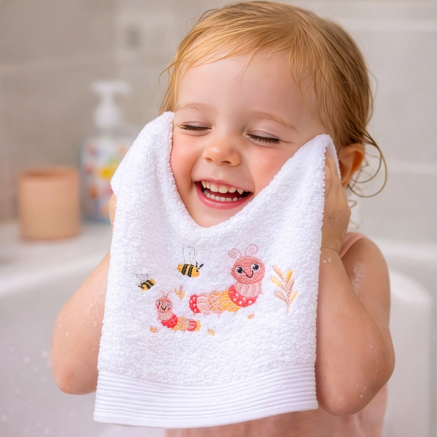 Baby girl using pink embroidered face washer from bath set