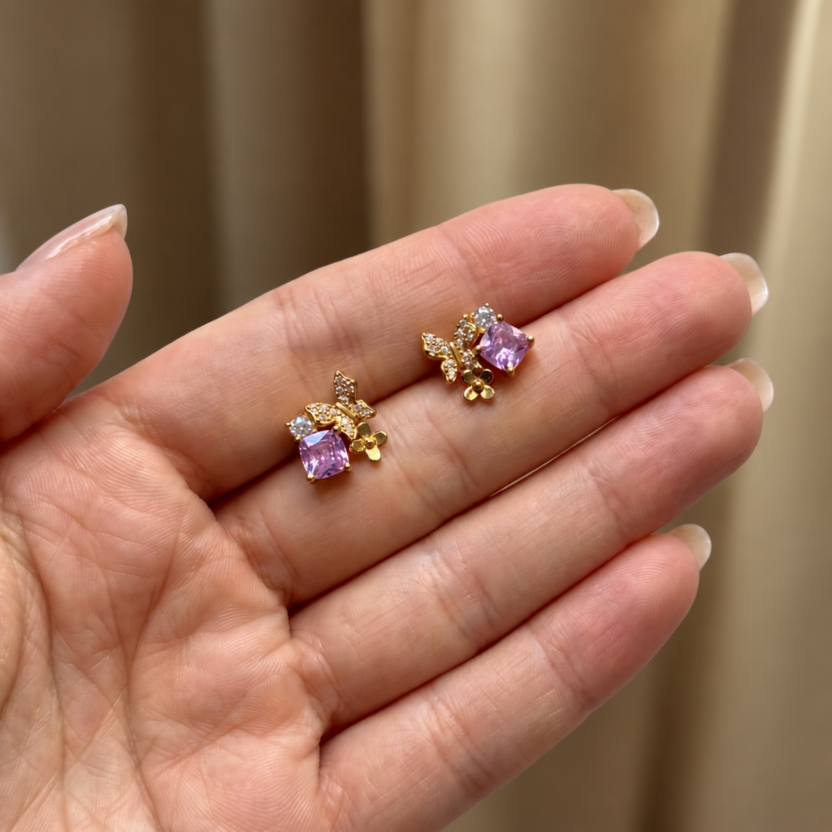 Pink Gold Butterfly Garden stud earrings held in hand to show their size